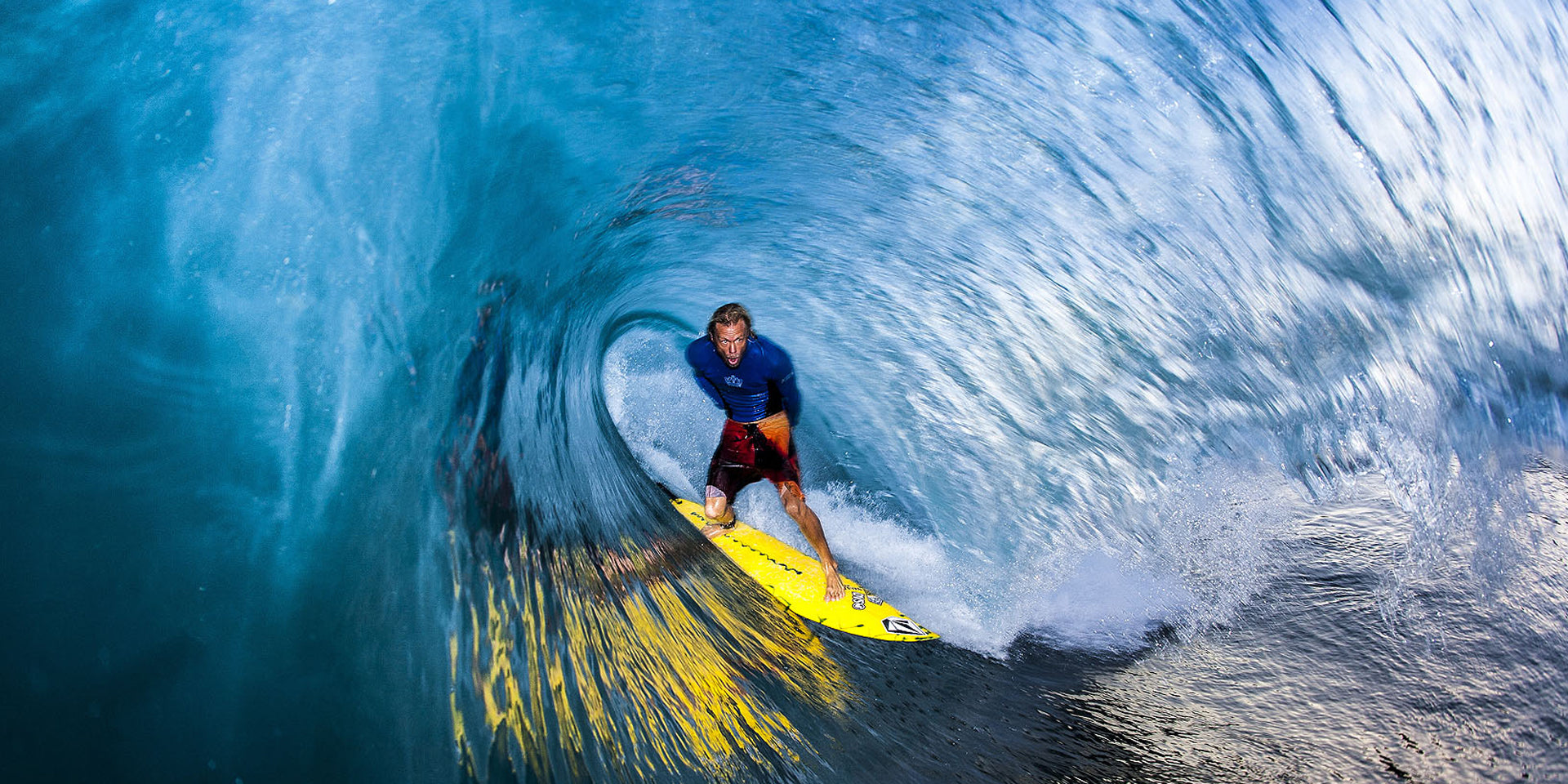 Dave “Nelly” Nelson photo of surfer on a yellow surfboard riding a powerful wave.