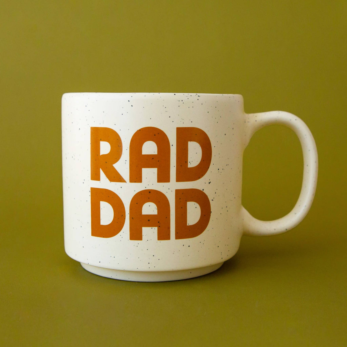 A white speckled ceramic mug with the words 'RAD DAD' printed in bold orange lettering, set against a solid olive green background.