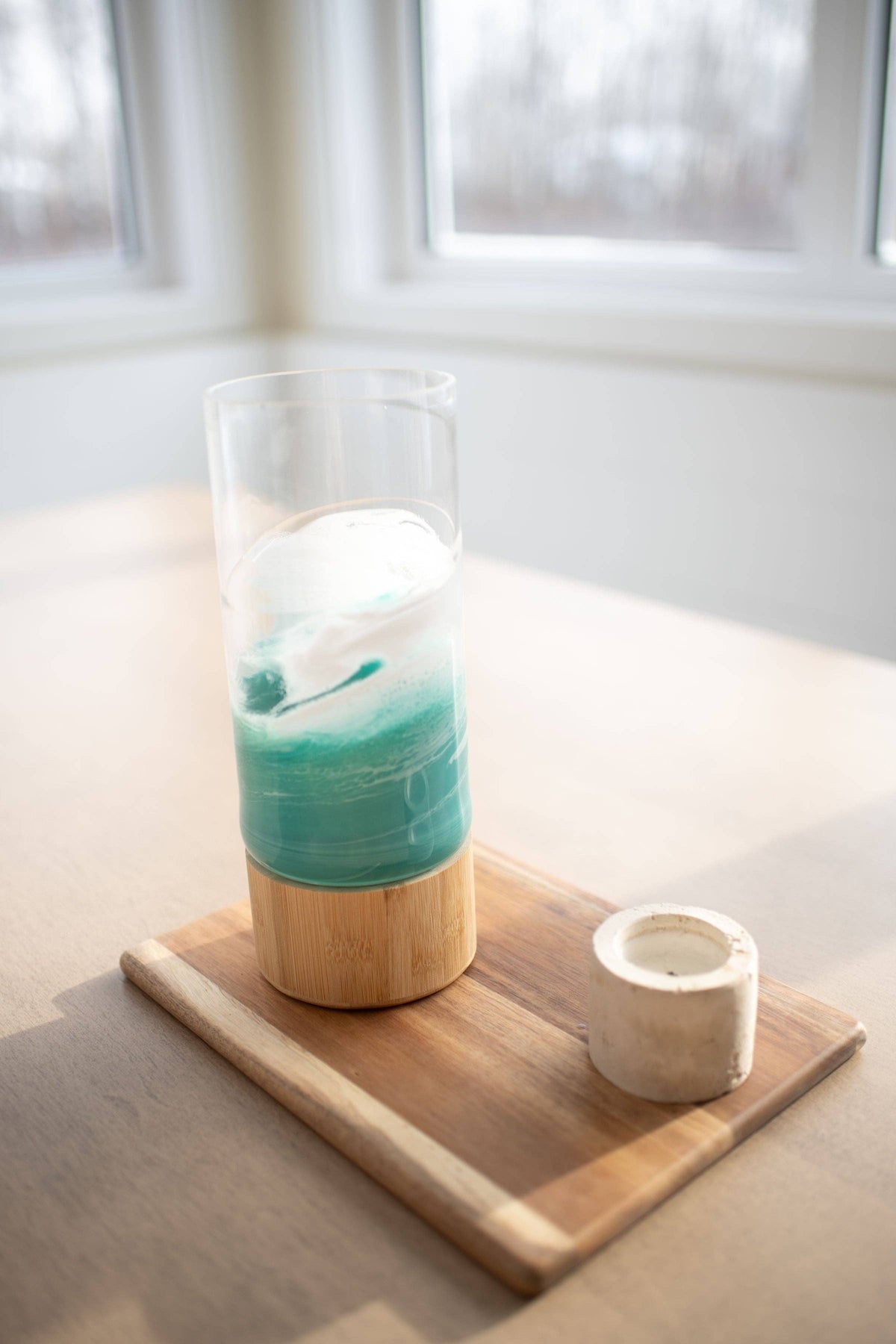 Candle in a glass holder with a wooden base on a table