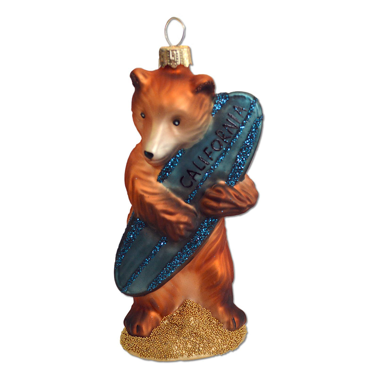A Christmas ornament shaped like a brown bear holding a blue glitter surfboard with the word 'CALIFORNIA' on it, standing on a gold glitter base against a white background.