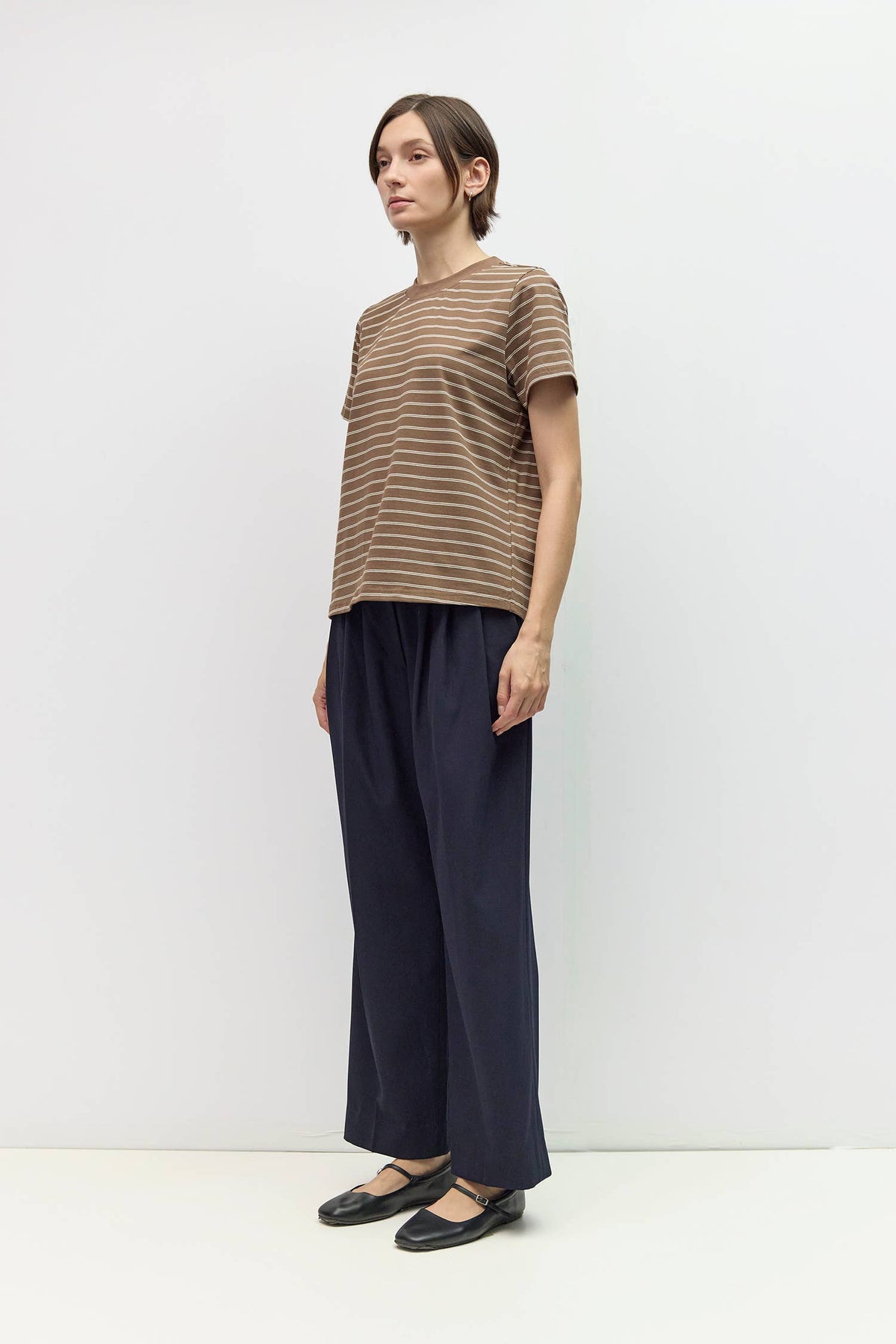 Person wearing a striped shirt and wide-leg pants on a white background