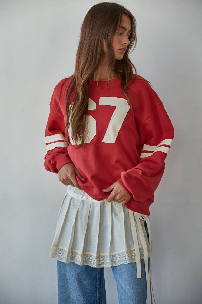 woman with red sweater on and jeans with a white background looking away because eye contact isn't as cool