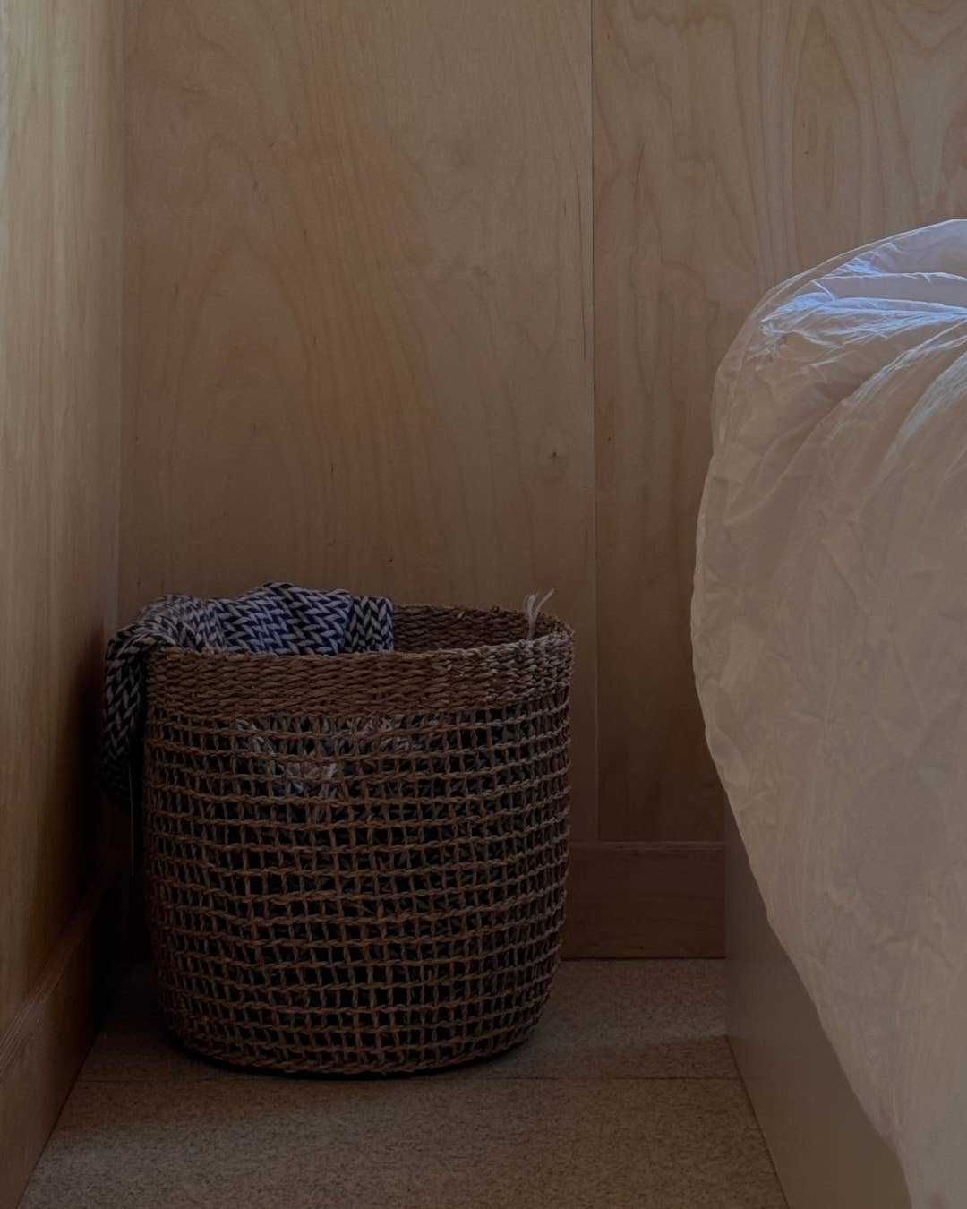 Wicker basket with clothes against a wooden wall.