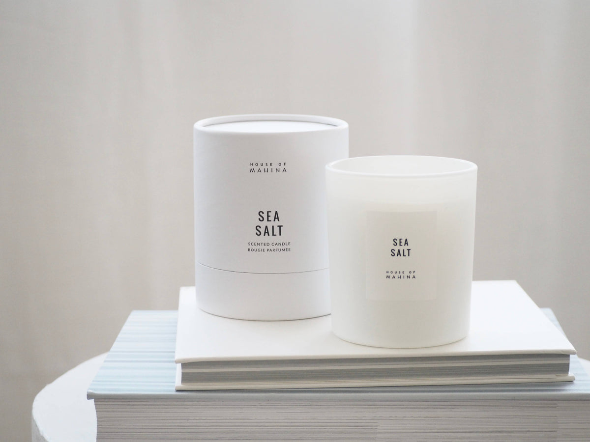 Two 'Sea Salt' candles on a stack of books with a plain background