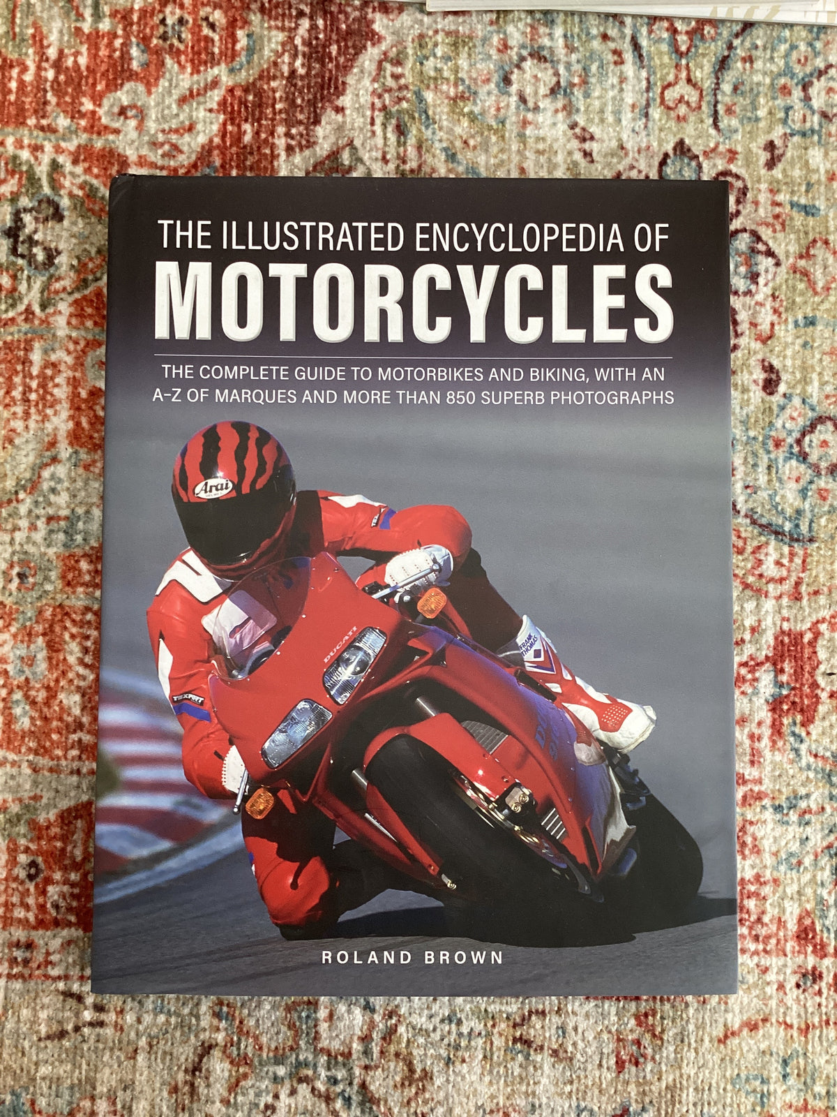 Book cover of 'The Illustrated Encyclopedia of Motorcycles' on a textured surface