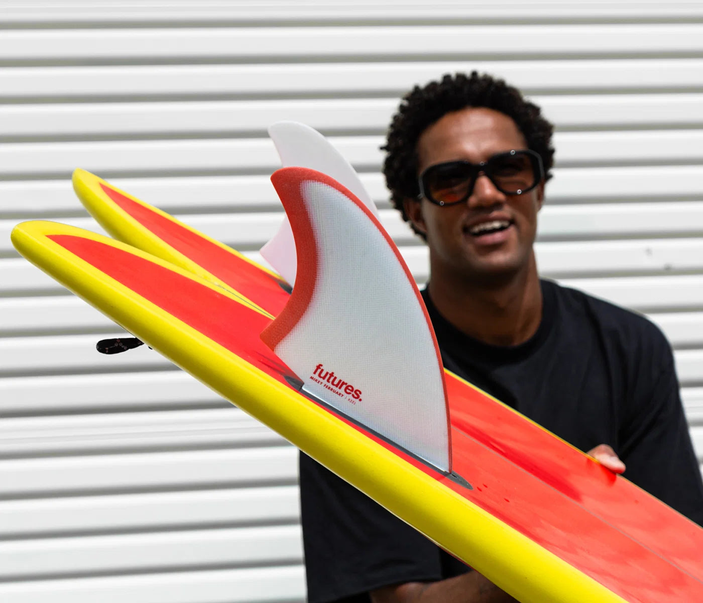Mikey February holding a surfbaord with Futures Mikey February Fiberglass Keel Fin Set