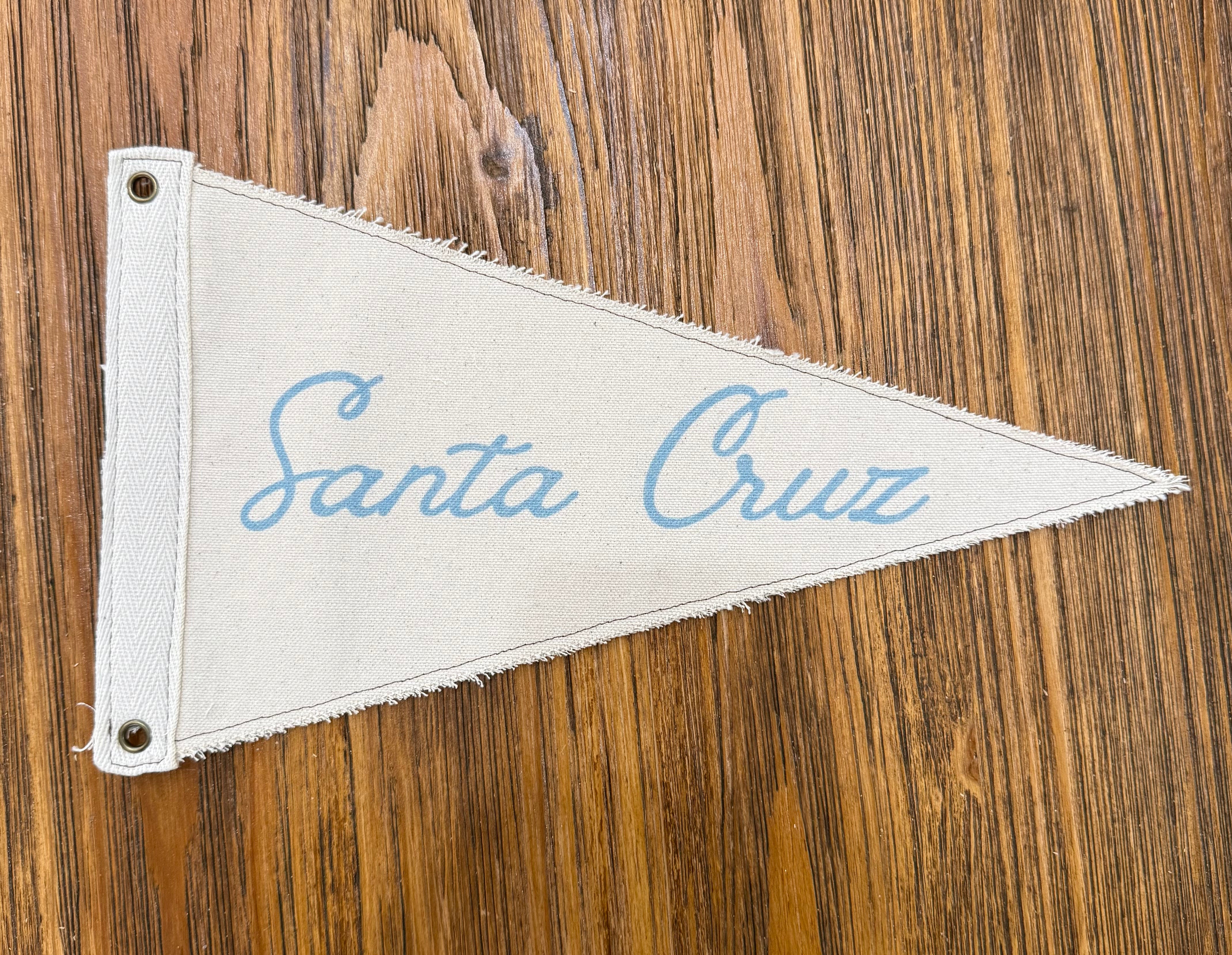 Fabric pennant with 'Santa Cruz' text on a wooden surface