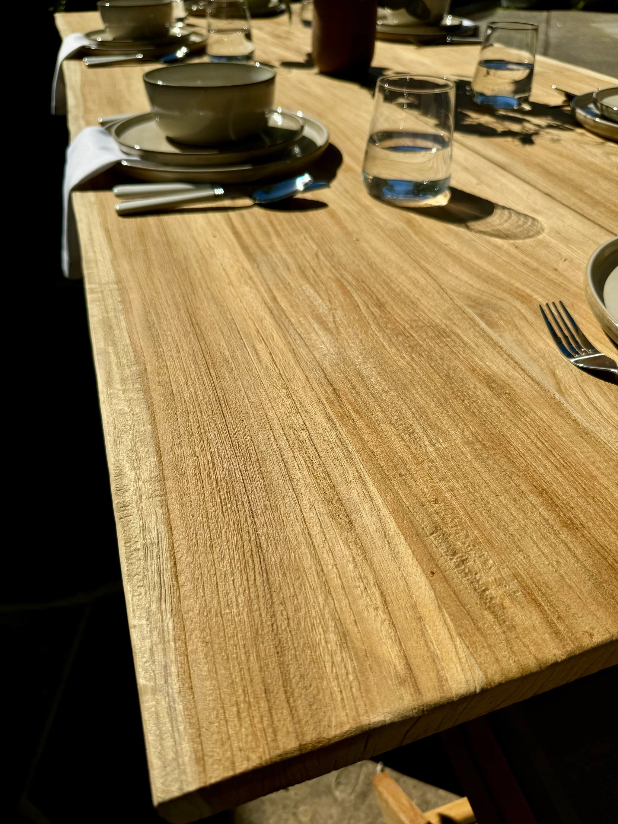Wooden dining table with plates, cups, and cutlery on a blurred background