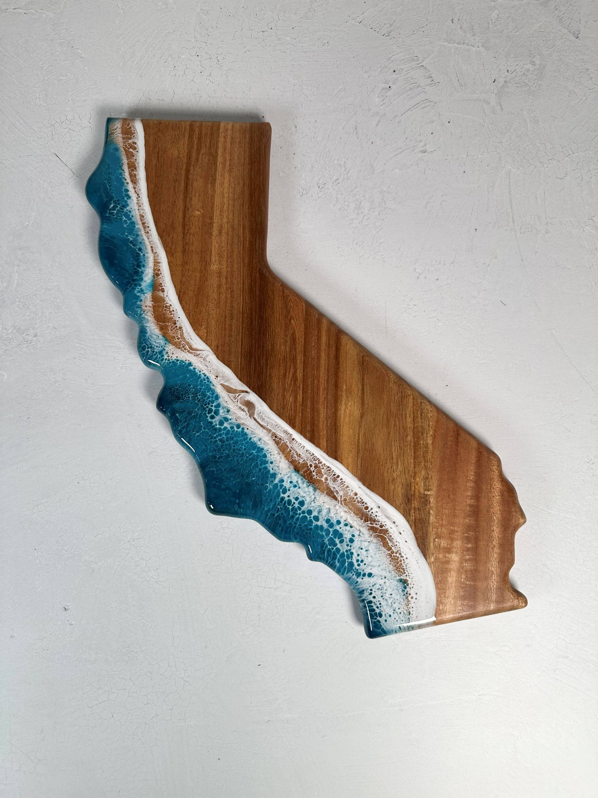 Wooden wall art shaped like the state of California with blue and white design