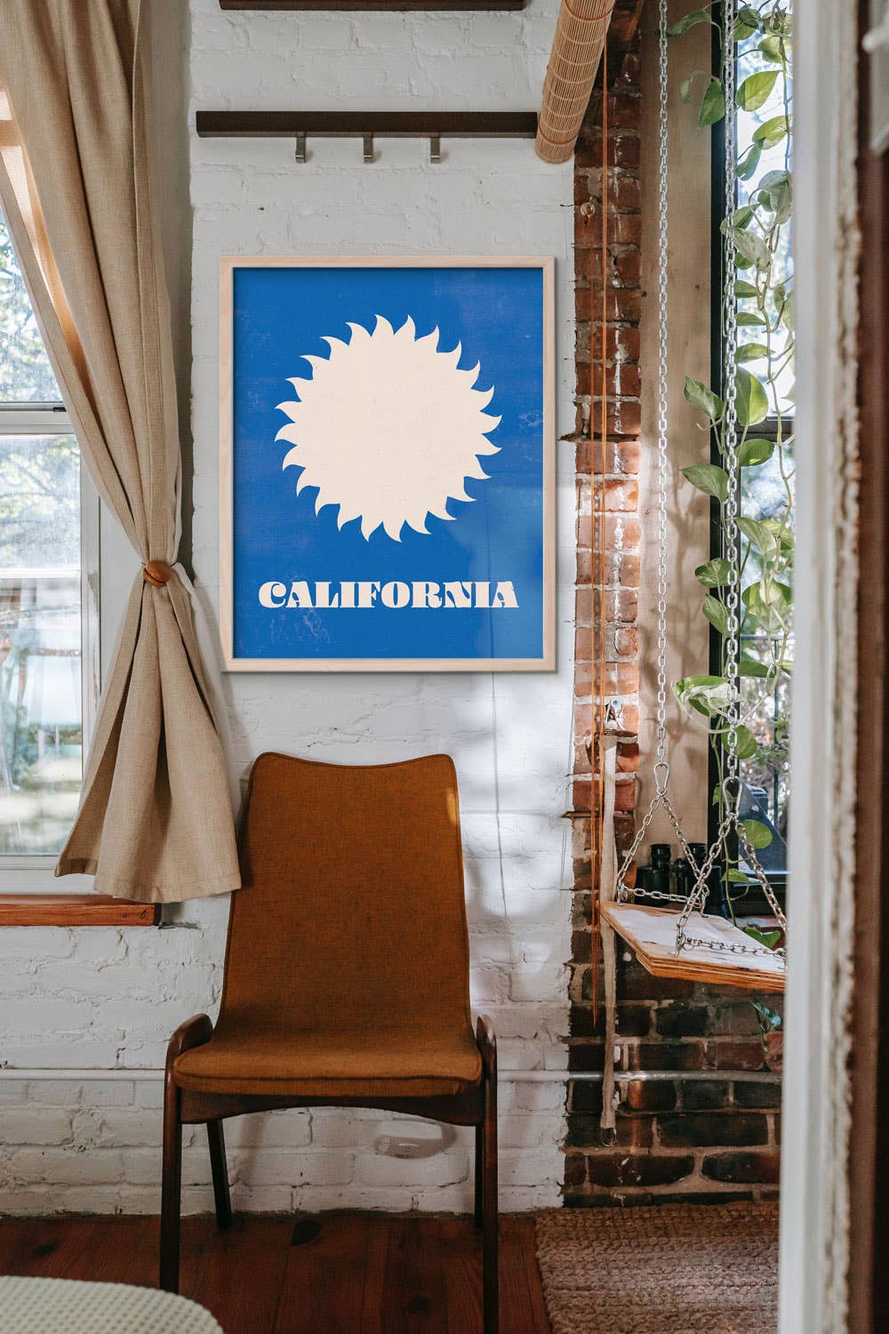 Room interior with a brown chair, California-themed artwork on the wall, and a brick wall.