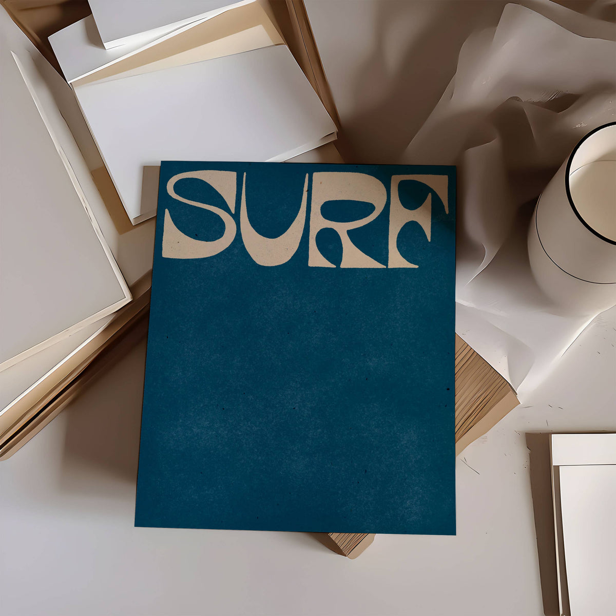 Blue book with 'SURF' text on a surface with books and a mug.