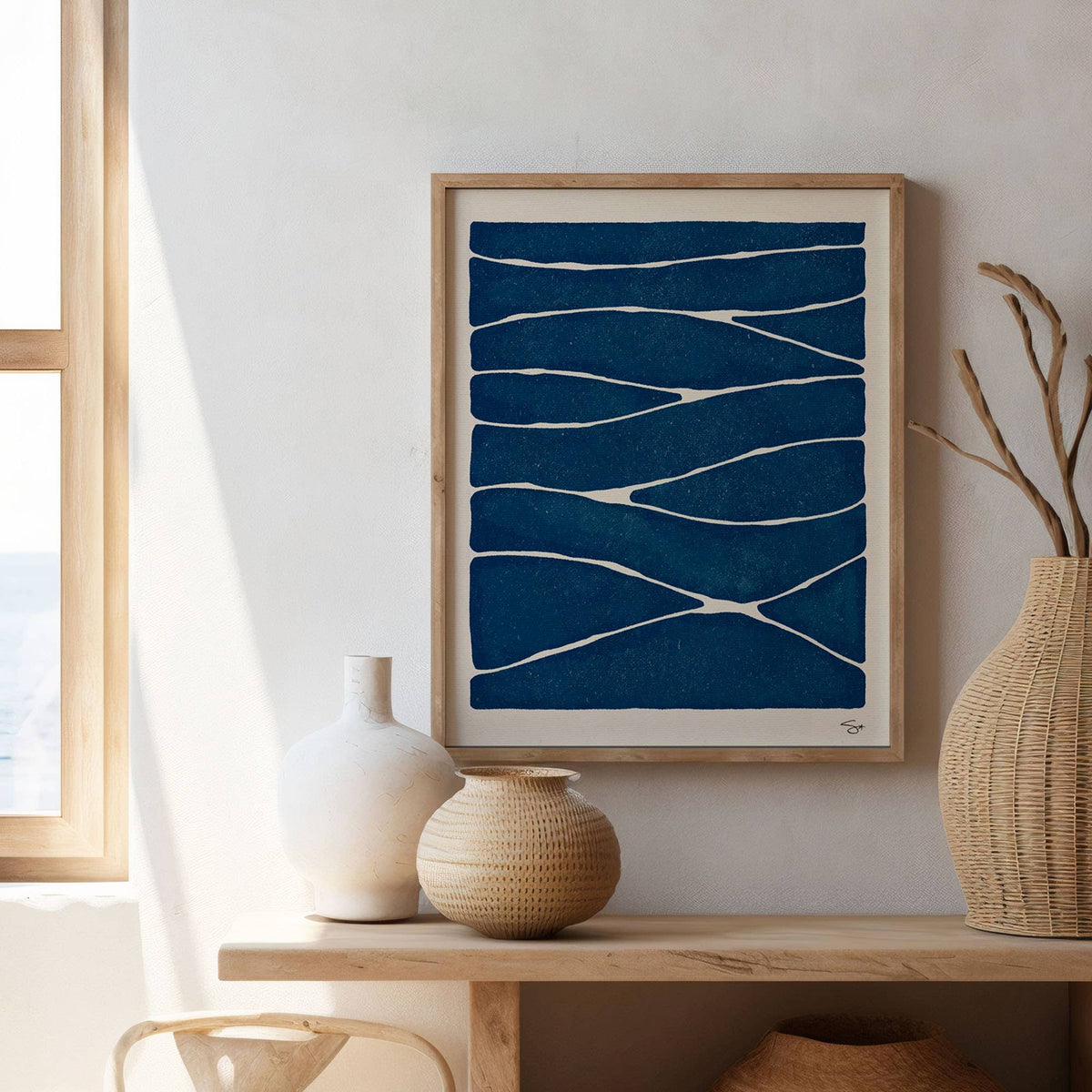Framed abstract art piece on a wall with decorative vases below.