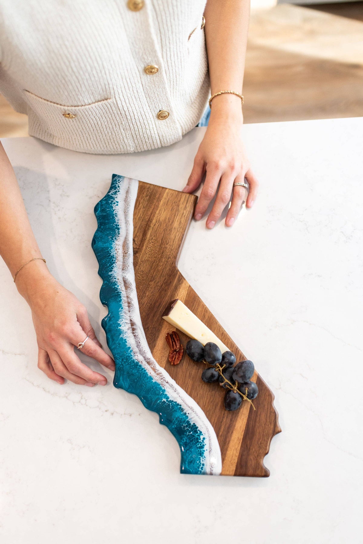 Wooden cutting board with blue resin design held by a person on a light background
