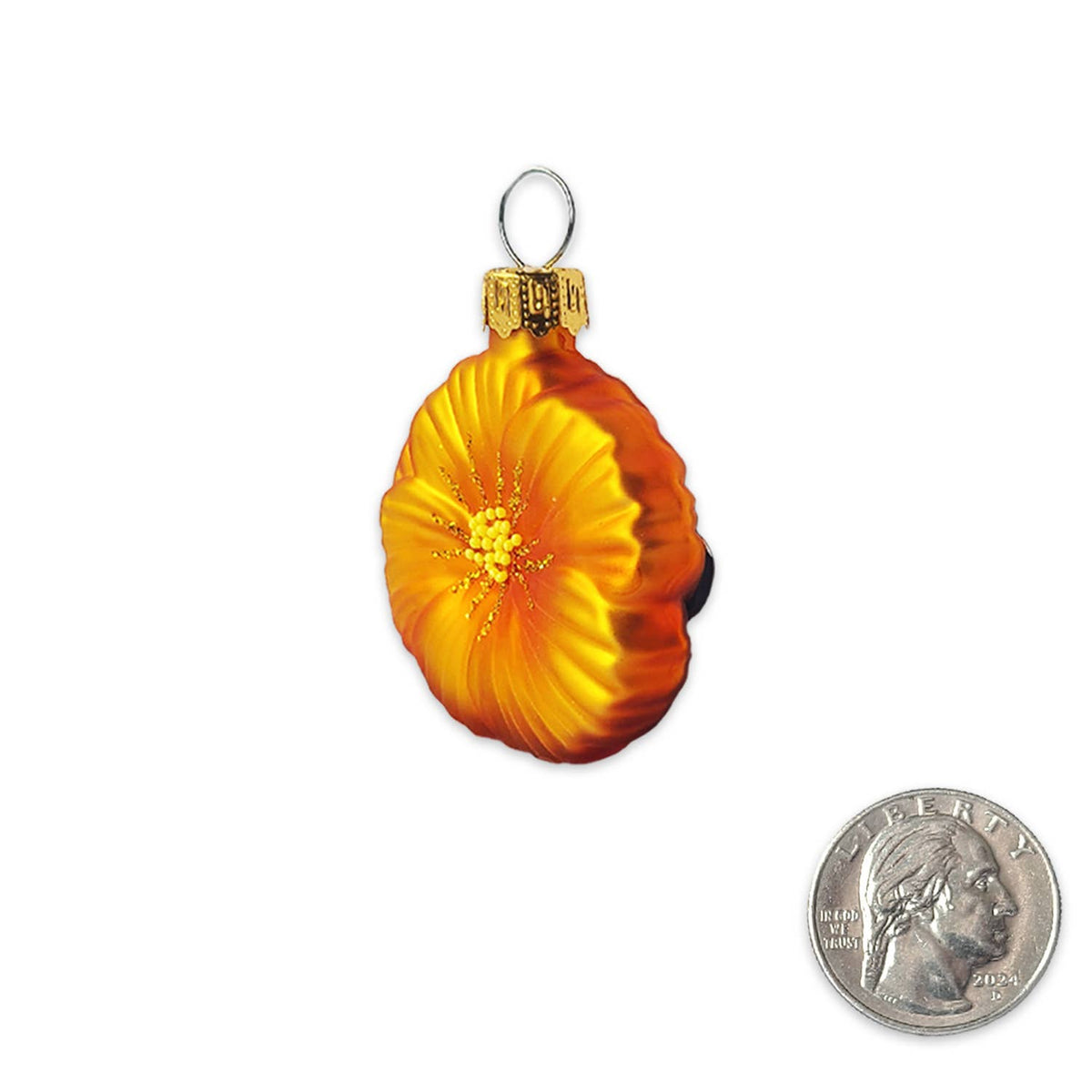A glass Christmas ornament shaped like a hibiscus flower in orange and yellow, shown next to a US quarter for scale on a white background.