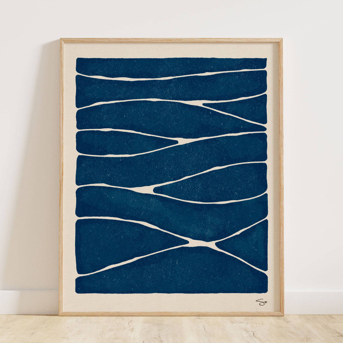 Framed abstract art print with blue and white pattern on a white wall.