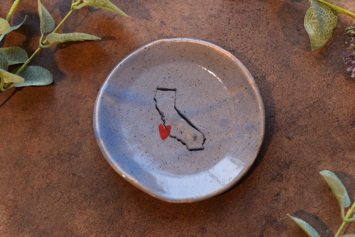Ceramic dish with a map of California and a red heart on a rustic surface