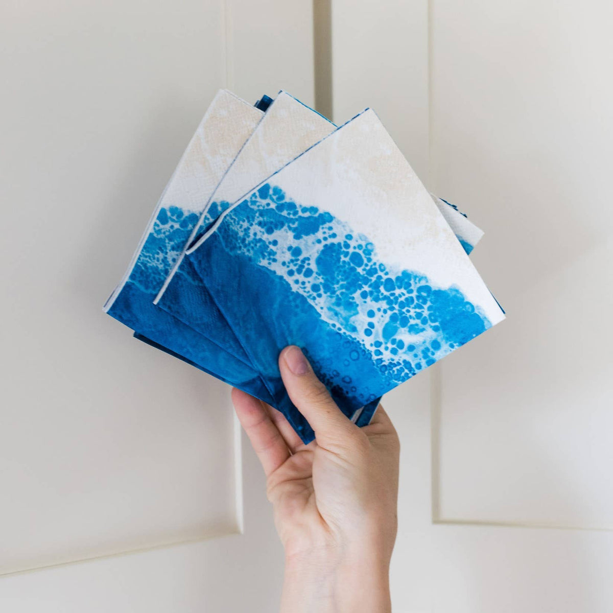 Hand holding a stack of blue and white patterned books against a light background