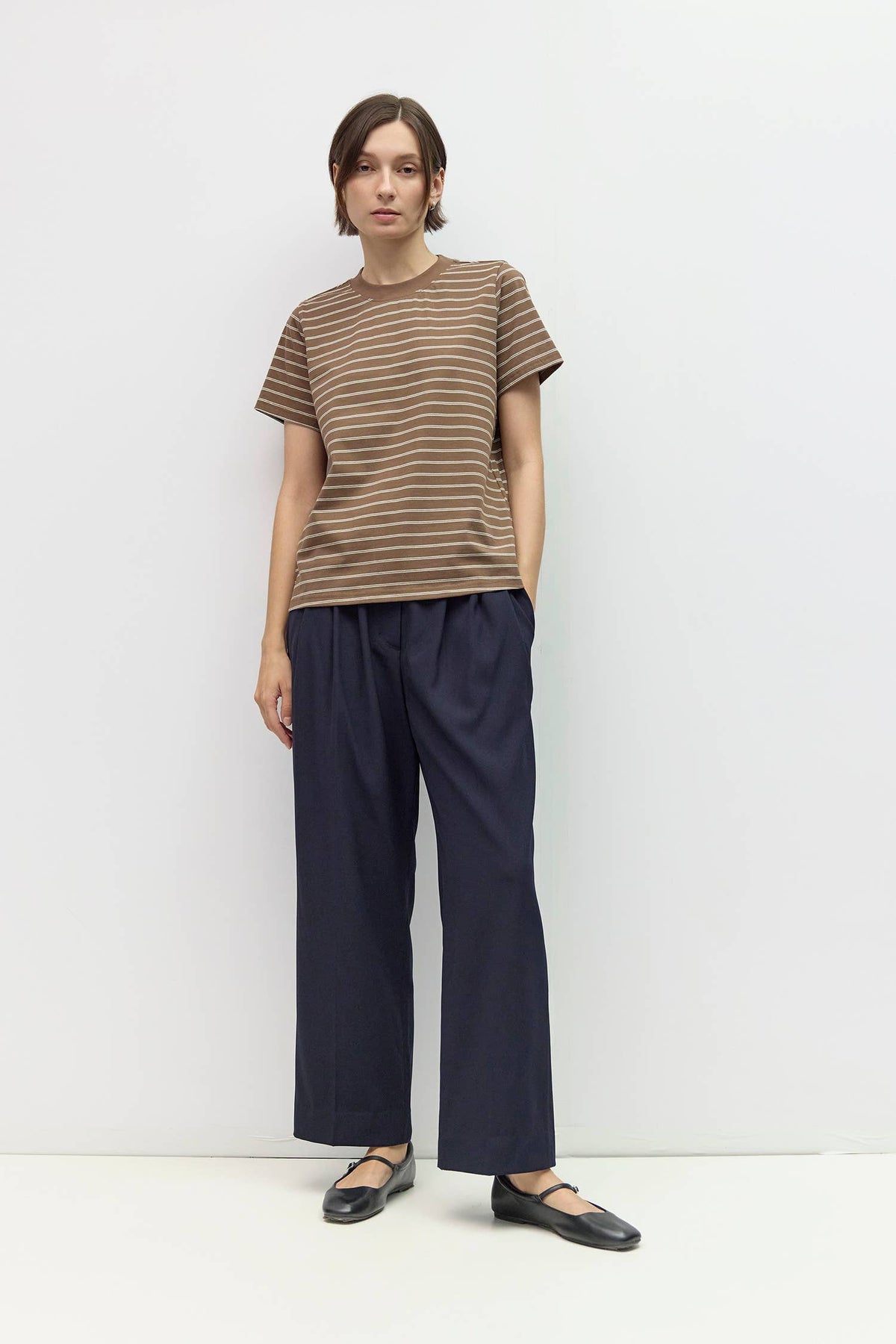 Person wearing a striped shirt and wide-leg pants against a white background