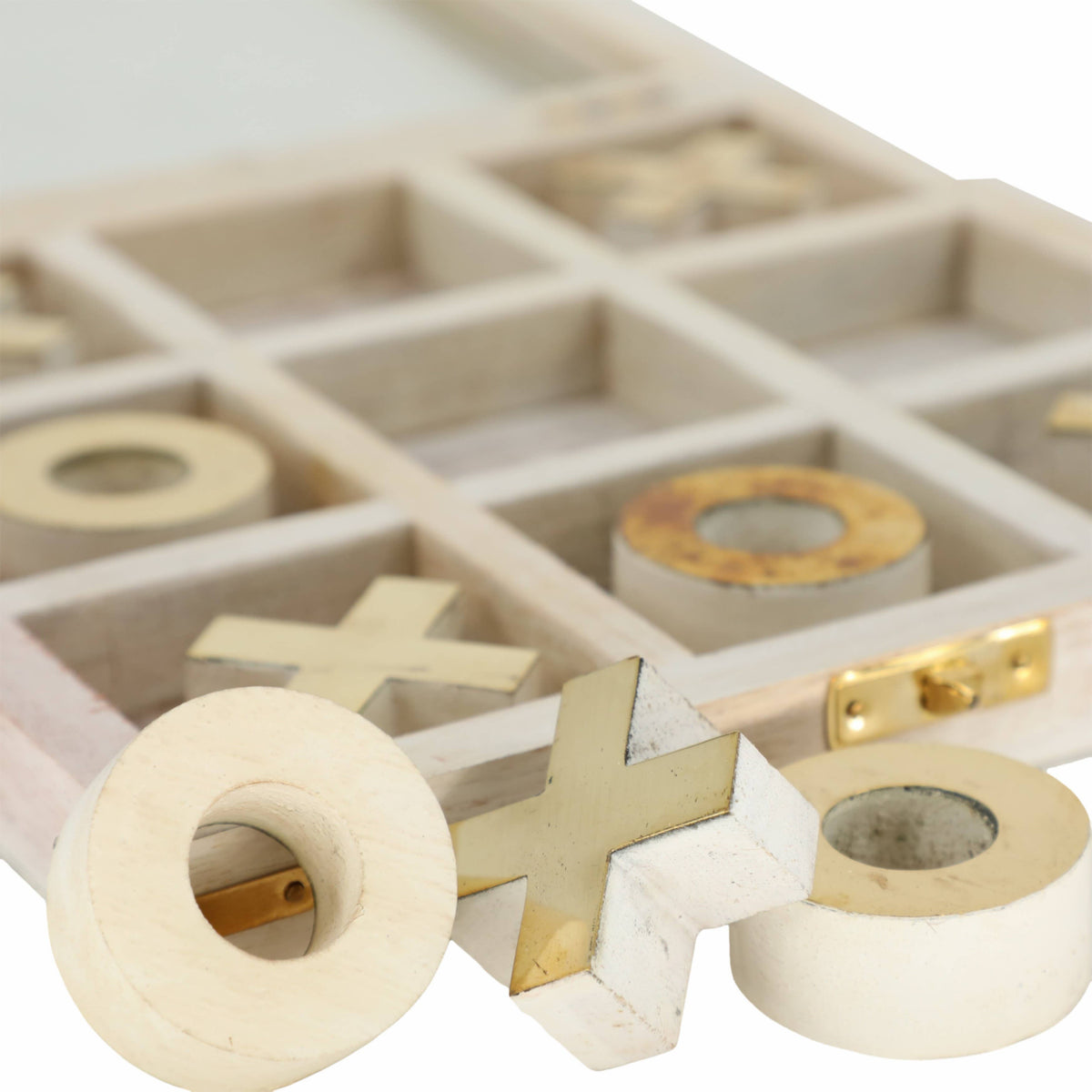 Close-up of a wooden tic-tac-toe game with gold pieces on a white background