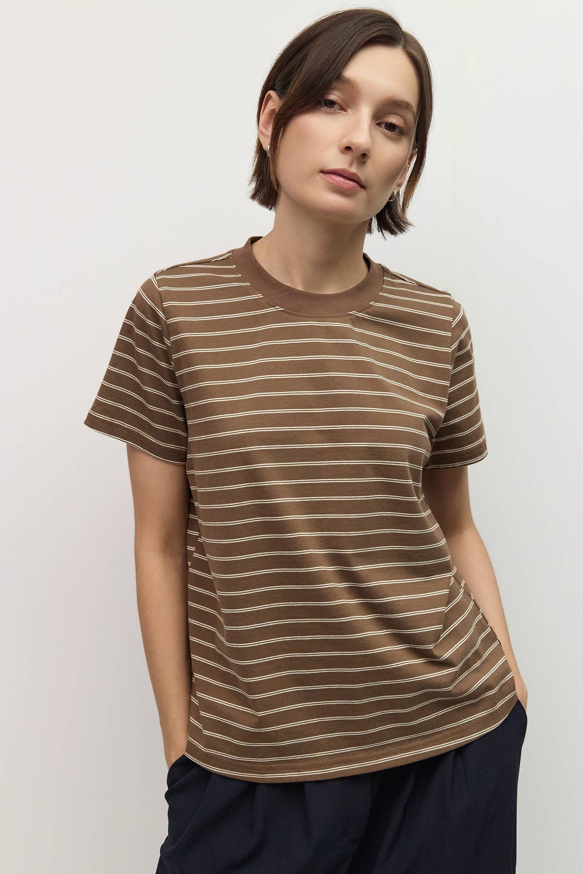 Person wearing a brown and beige striped t-shirt against a plain background