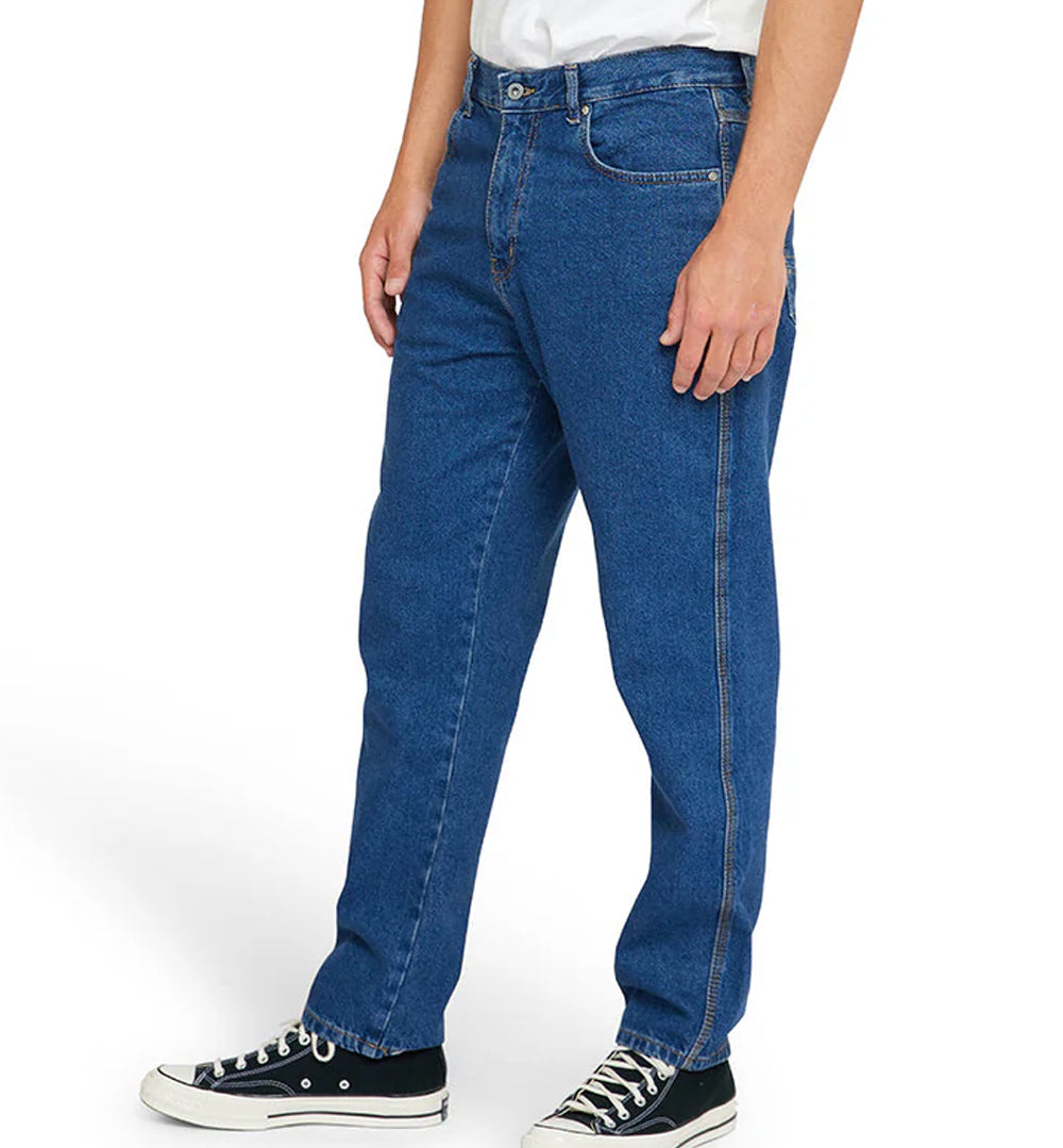 Person wearing blue jeans and black sneakers on a white background