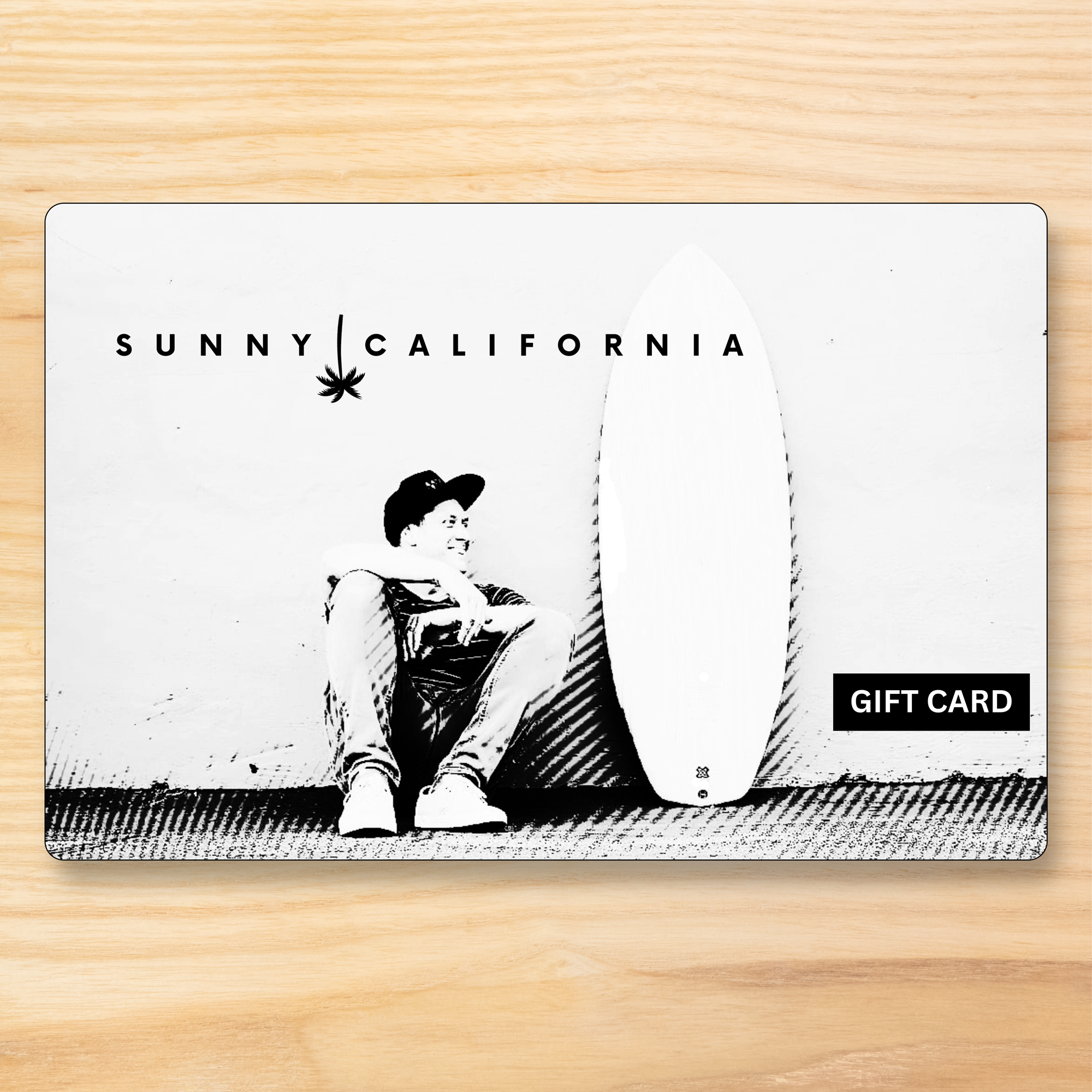 Gift card with a person holding a surfboard and 'Sunny California' branding on a wooden surface.