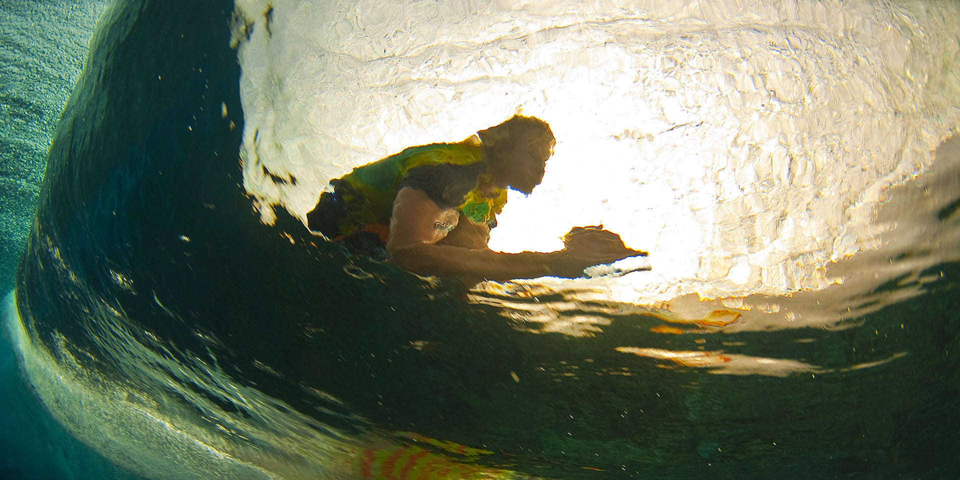 Dave “Nelly” Nelson photo of person surfing inside a wave with sunlight filtering through