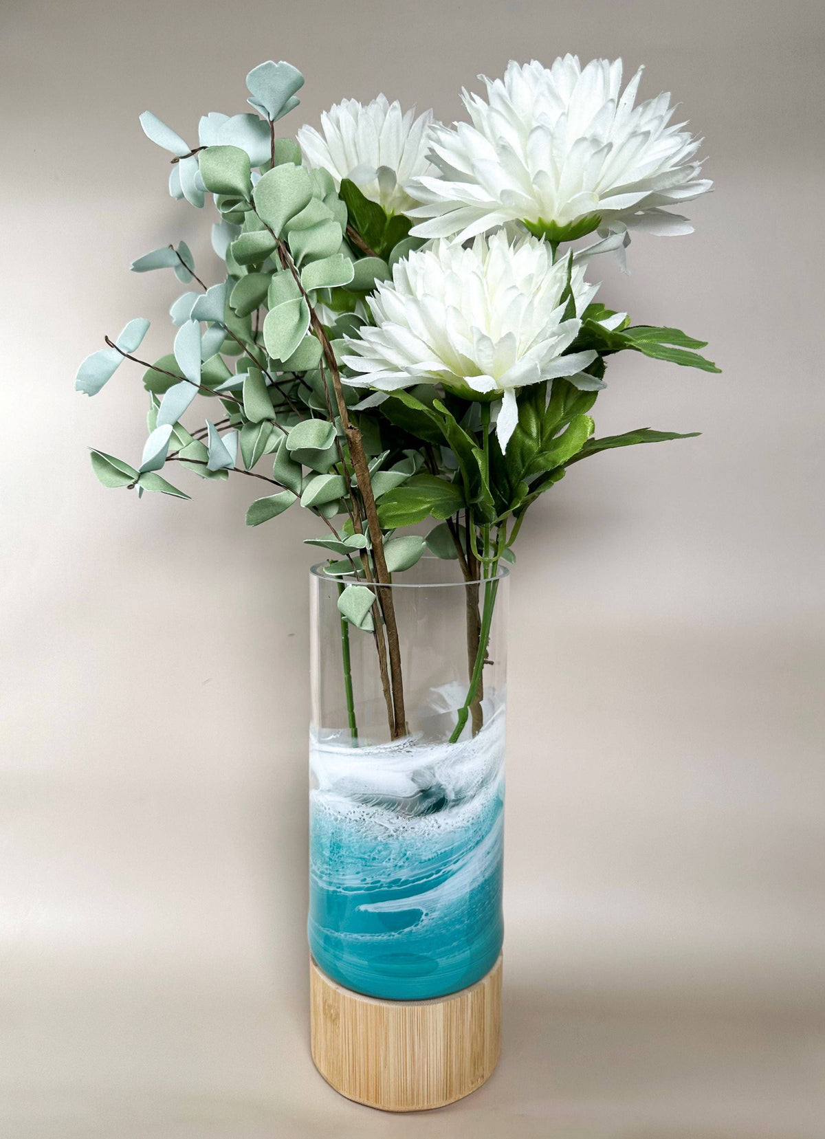 Vase with white flowers and greenery on a plain background