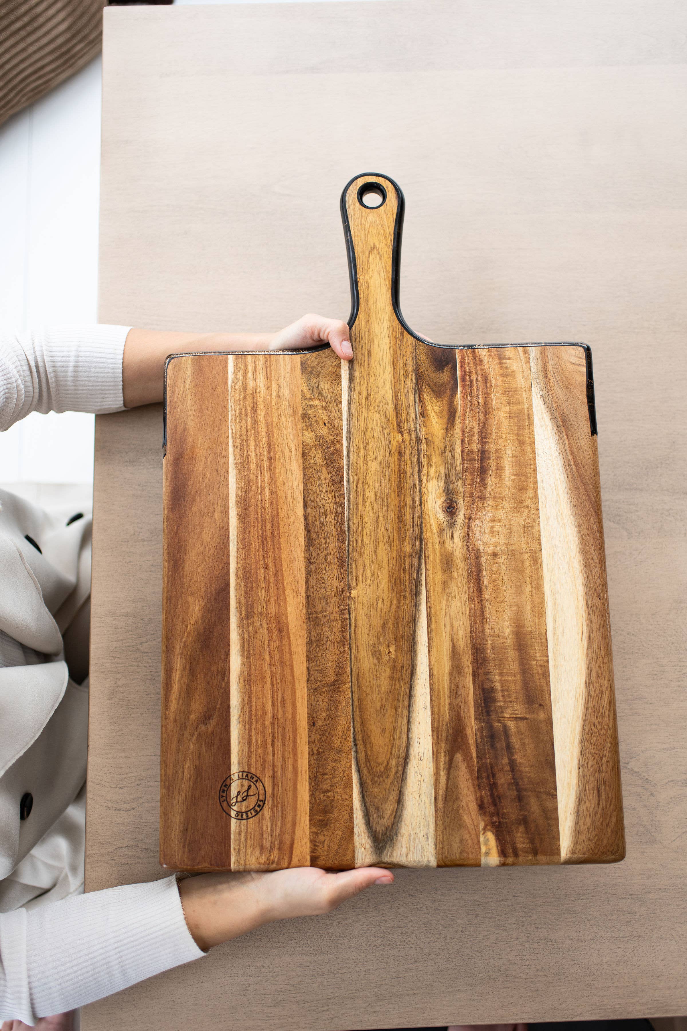 Wooden cutting board with a person holding it on a neutral background