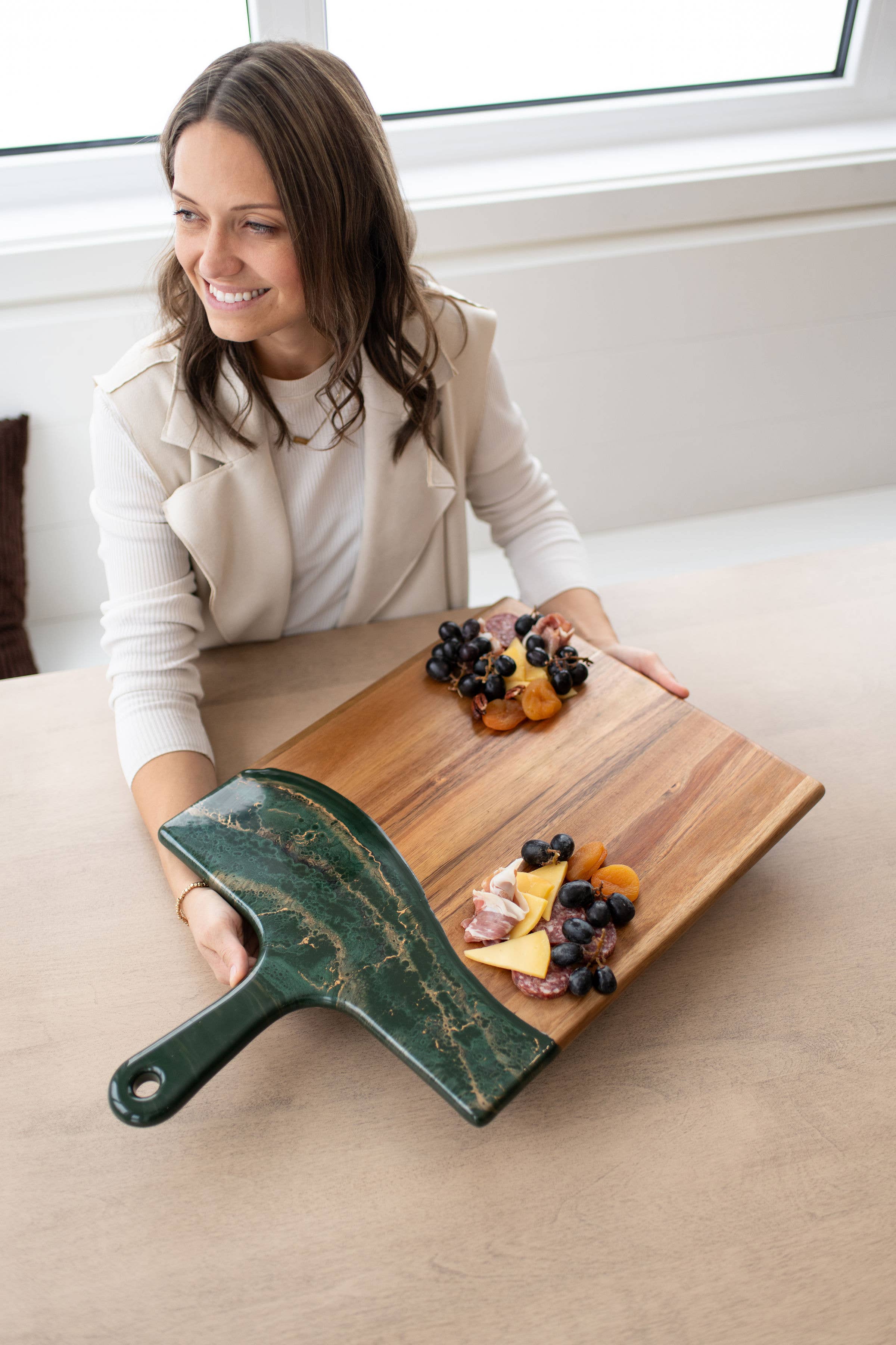 Woman sitting at a table with a wooden cutting board and green handle