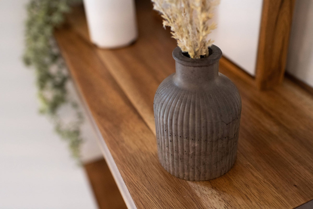 Decorative vase with dried flowers on a wooden shelf