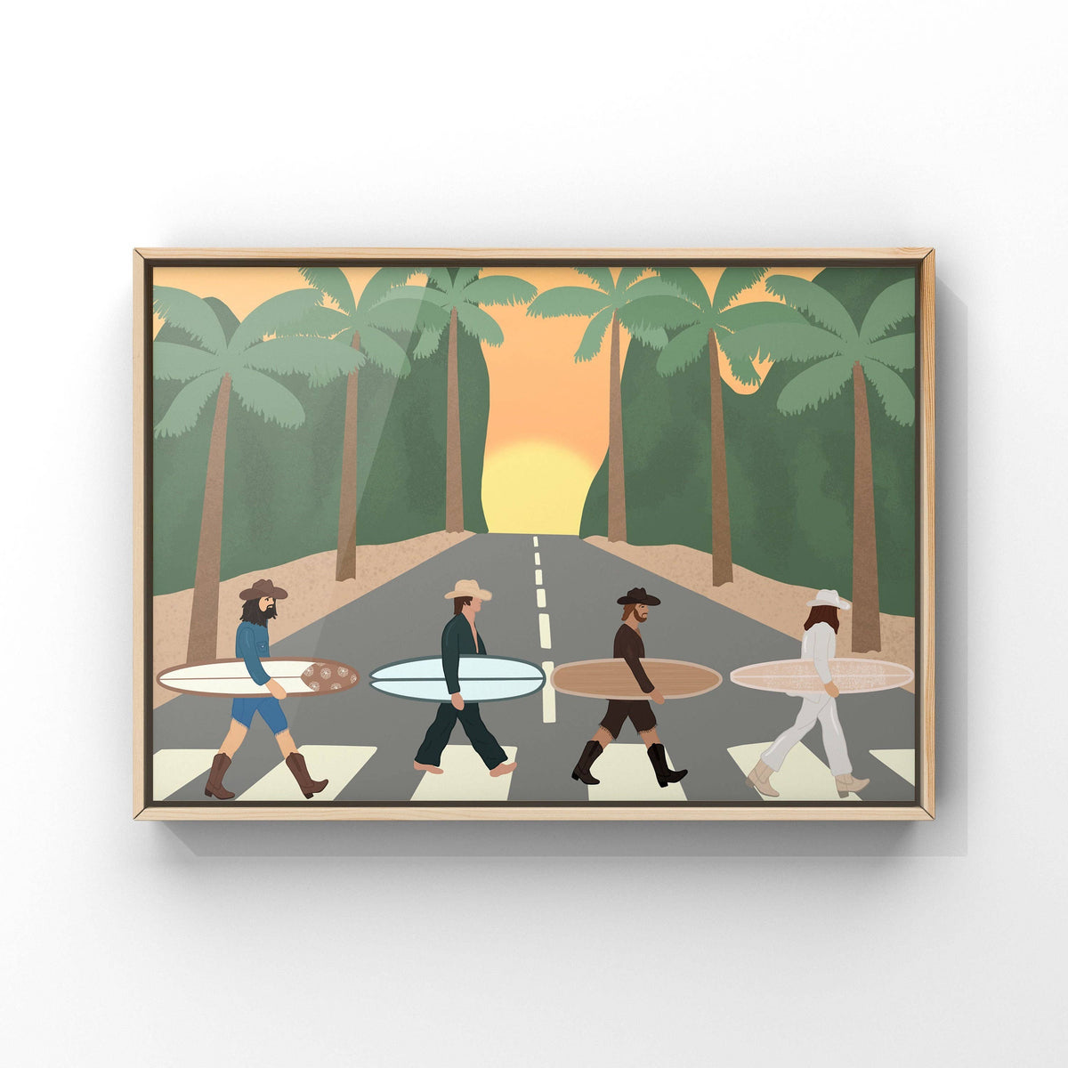 A framed art print depicting a stylized parody of the Beatles 'Abbey Road' scene, with four surfers walking across a zebra crossing under palm trees at sunset. The print is shown hanging on a light gray wall.