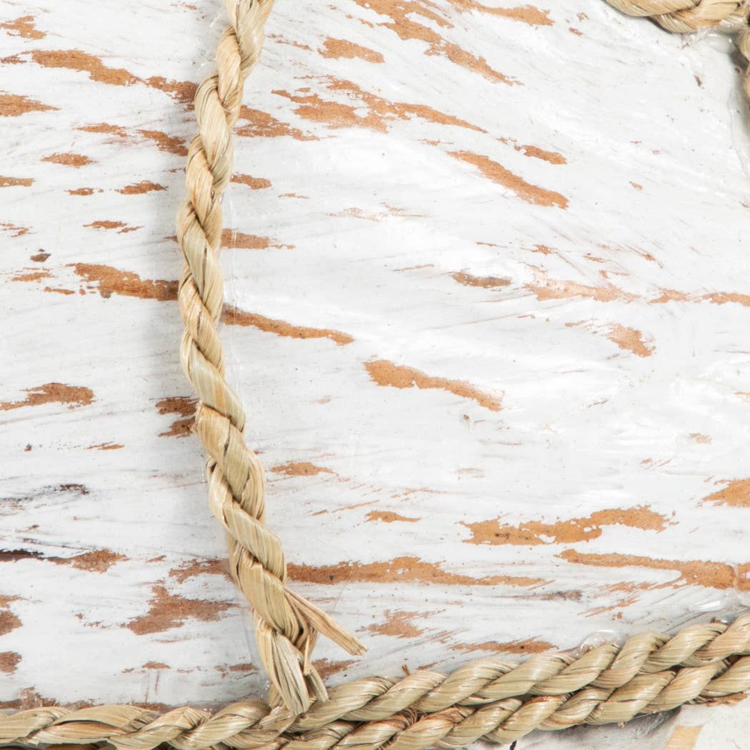 Close-up of a natural beige braided rope laid over a distressed white wooden surface with exposed tan wood grain.