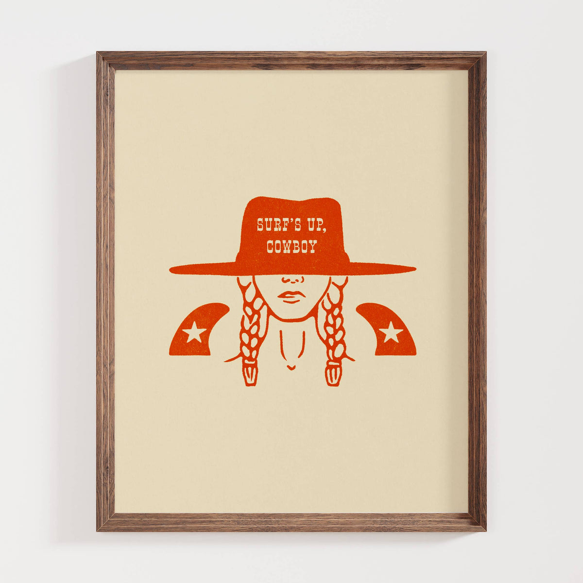 Framed artwork with a person wearing a cowboy hat and 'Surf's Up, Cowboy' text on a beige background.