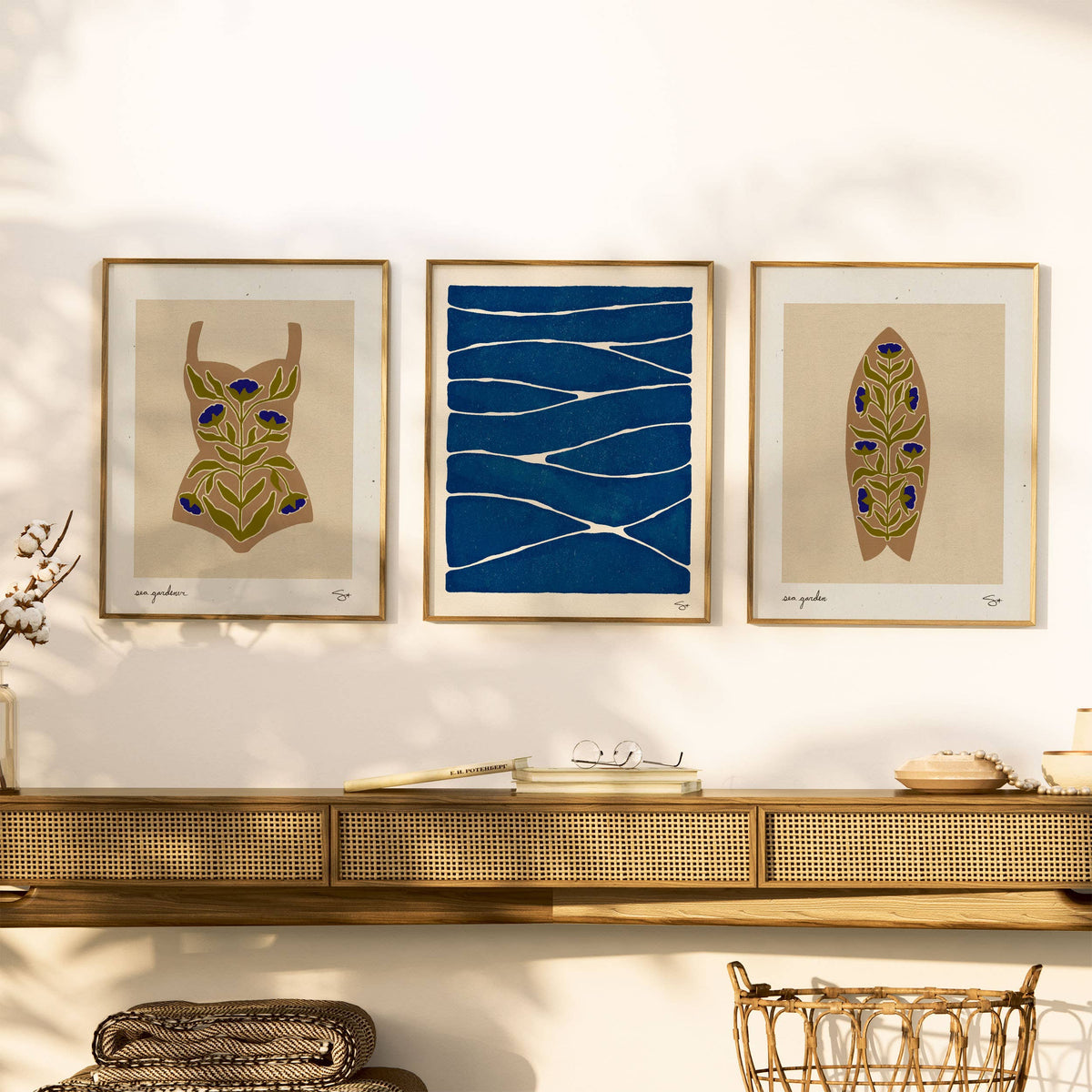 Three framed artworks on a wall above a console table with decorative items.