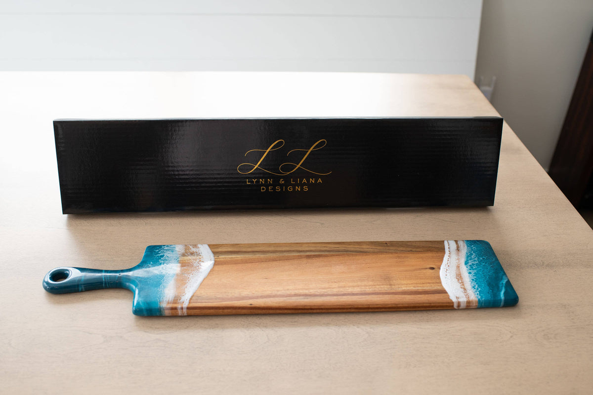 Wooden cutting board with blue and white design on a wooden surface, branded 'L&L'.