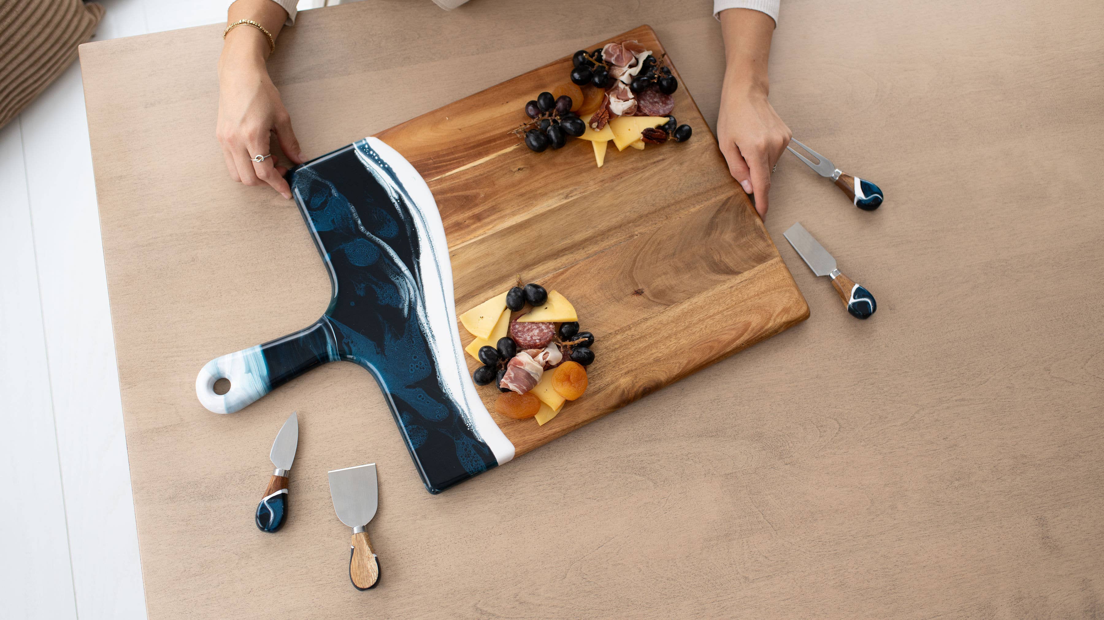 Wooden cutting board with cheese and fruit platter on a wooden surface