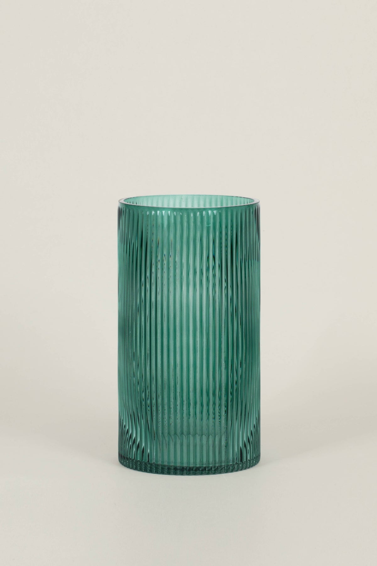 A tall, ribbed glass vase in a translucent teal green color, set against a plain light gray background.