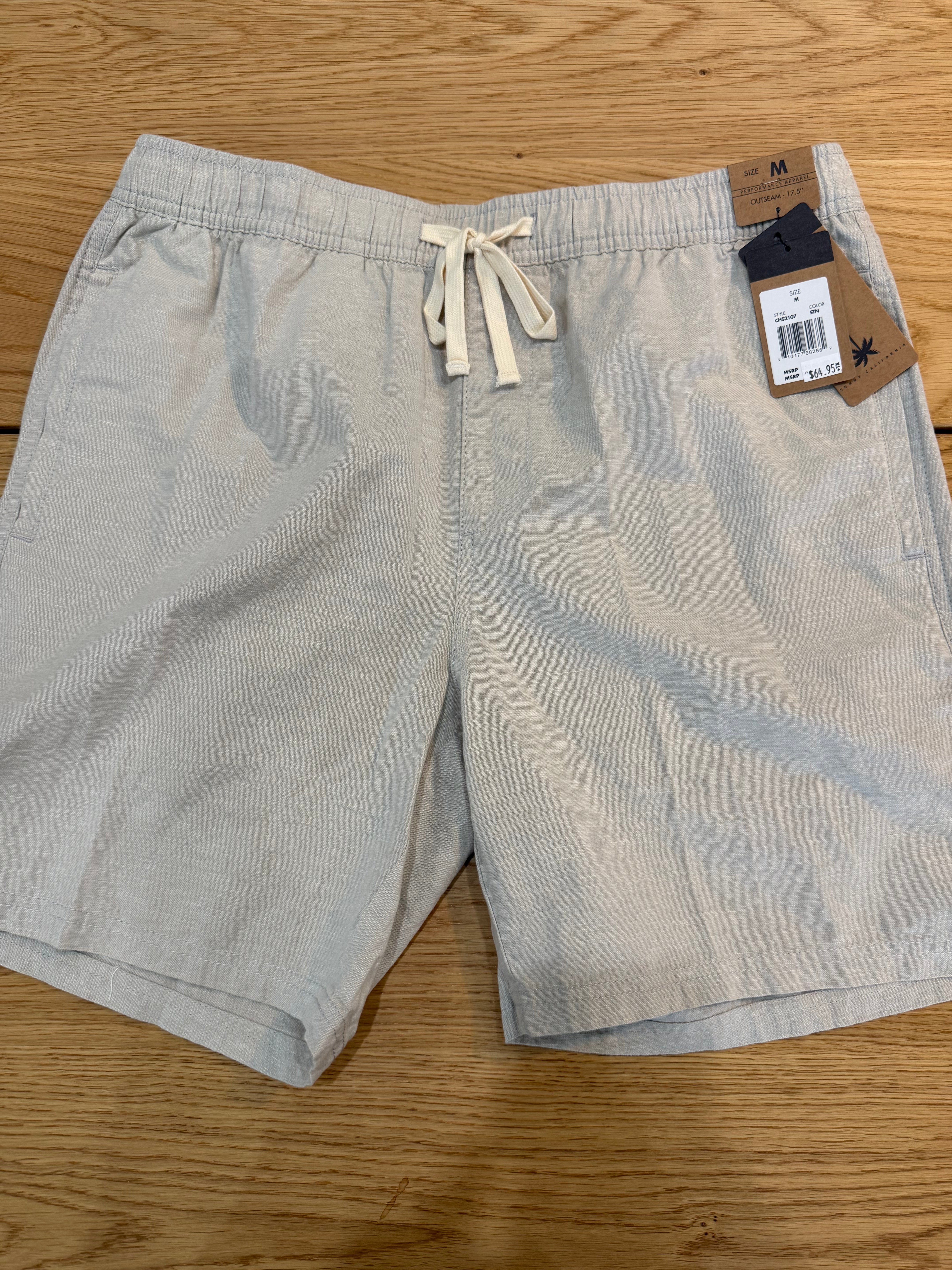 Light gray shorts with a brand tag on a wooden surface