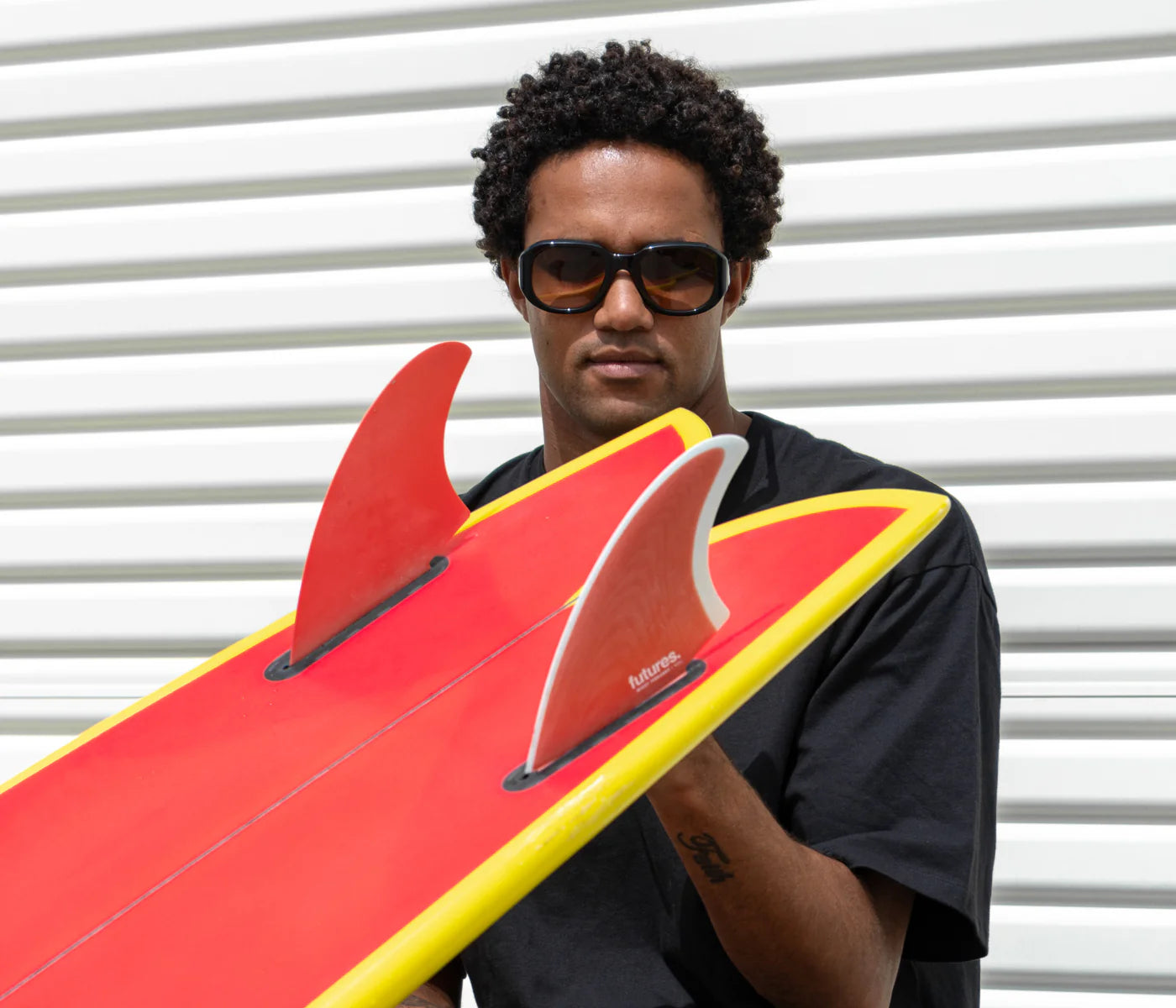 Mikey February holding a Futures Mikey February Fiberglass Keel Fin Set on a surfboard