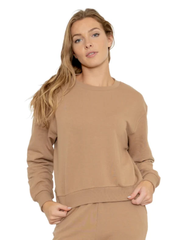 woman earing a stone brown colored sweat shirt on a white background.