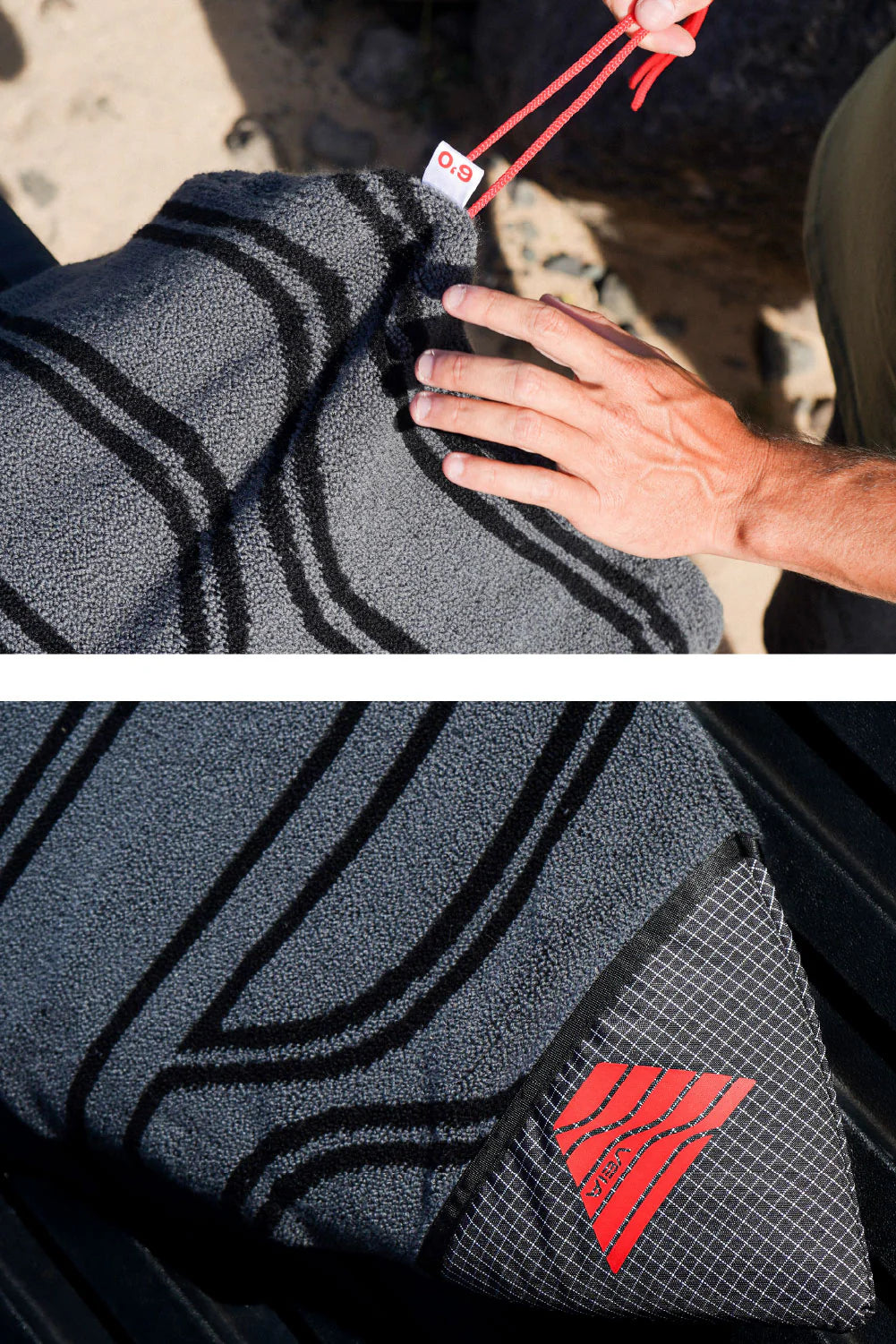 Close-up of a gray towel with a red logo being held by a person, with a focus on texture and branding.