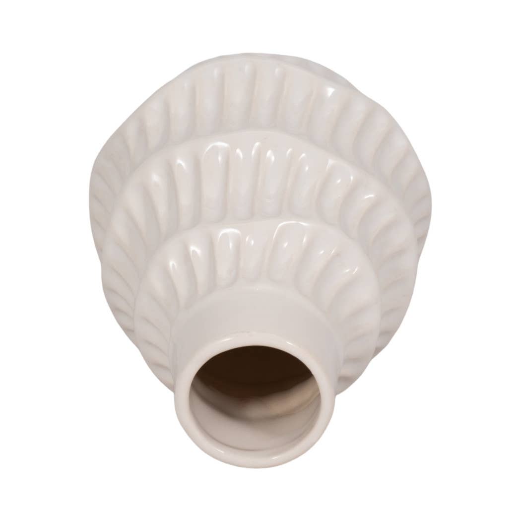 A white ceramic vase with a ribbed, scalloped fluted pattern and a cylindrical opening, shown against a plain white background.