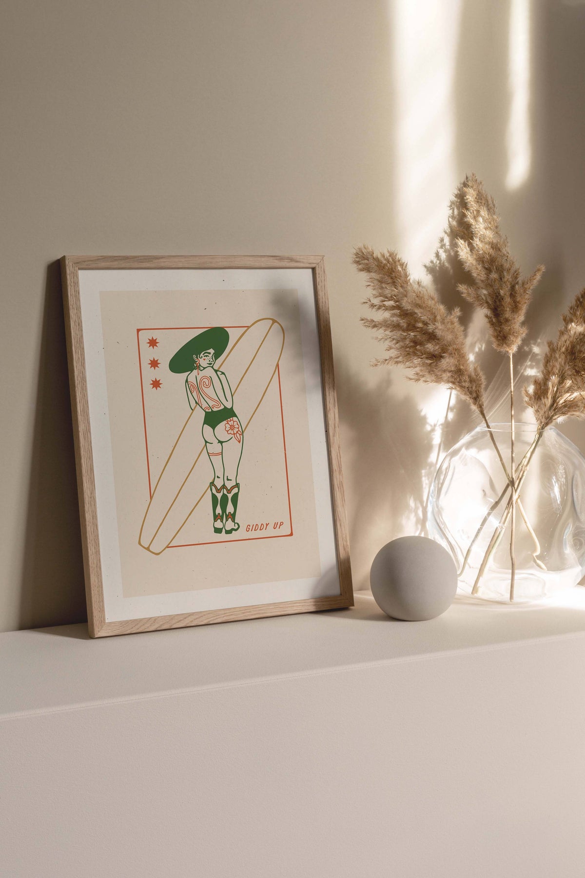 Framed artwork of a person with a surfboard on a shelf with decorative elements.