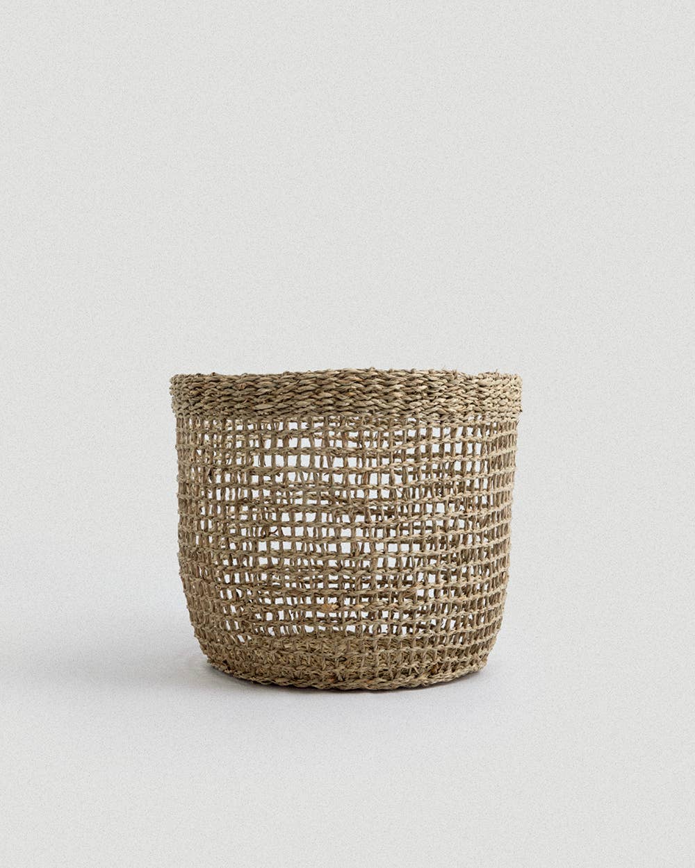Woven basket made of natural material on a light gray background