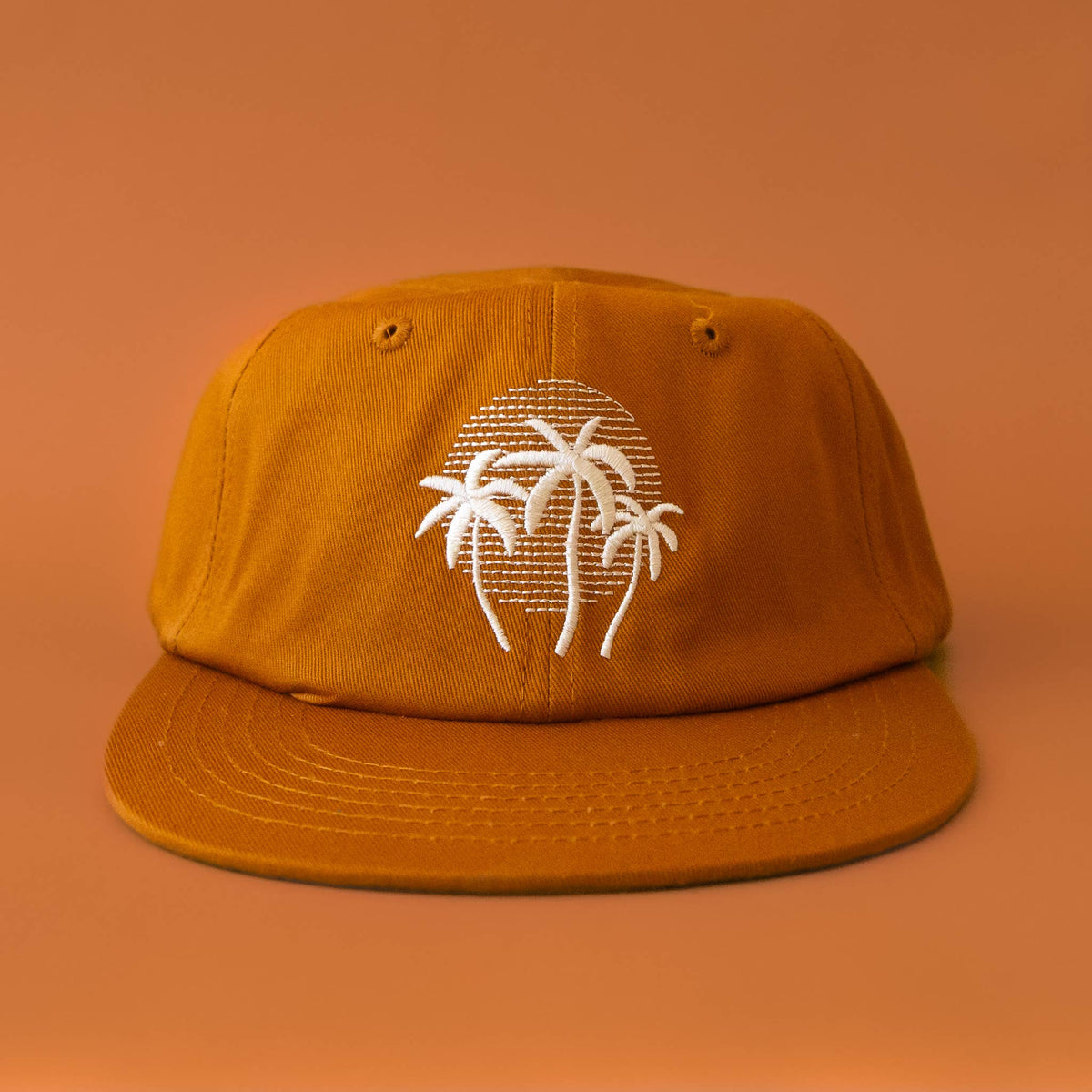 Orange cap with white palm tree design on an orange background