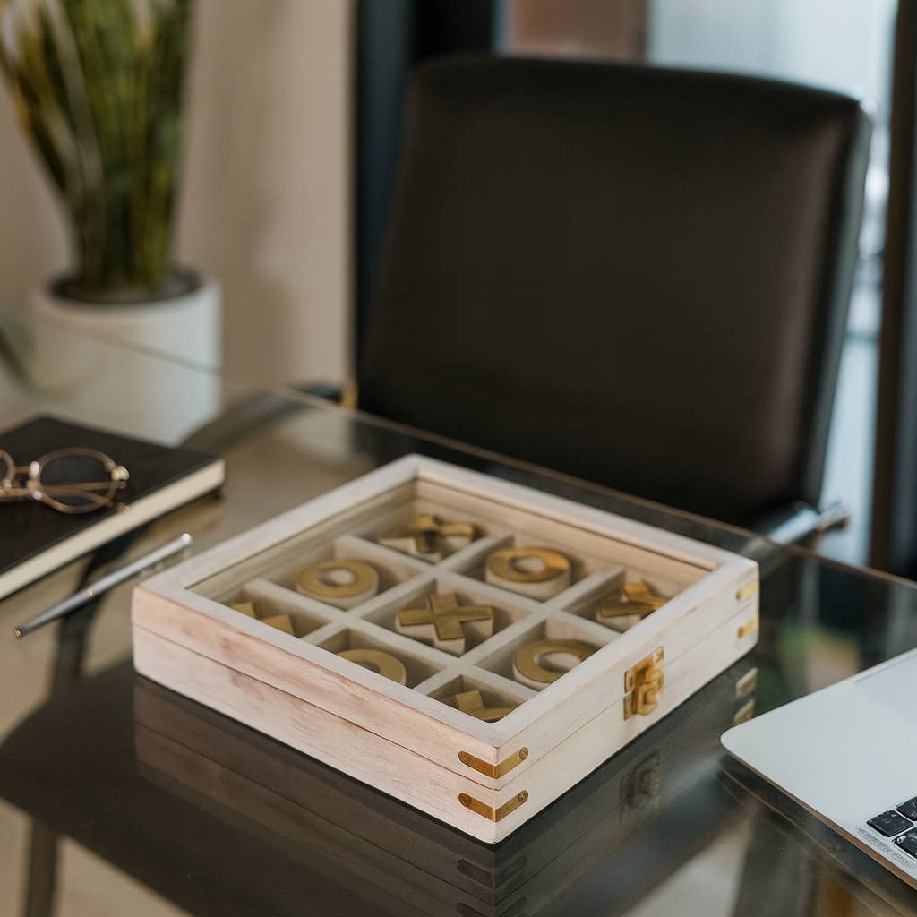 Wooden box with gold circular objects on a desk with a laptop and glasses in the background.