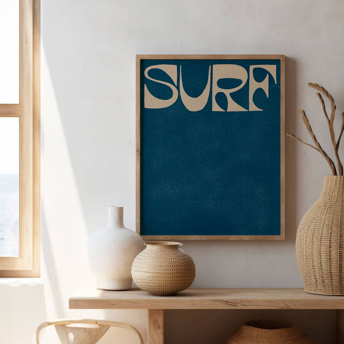 Framed artwork with 'SURF' text on a wall above a wooden shelf with decorative vases.