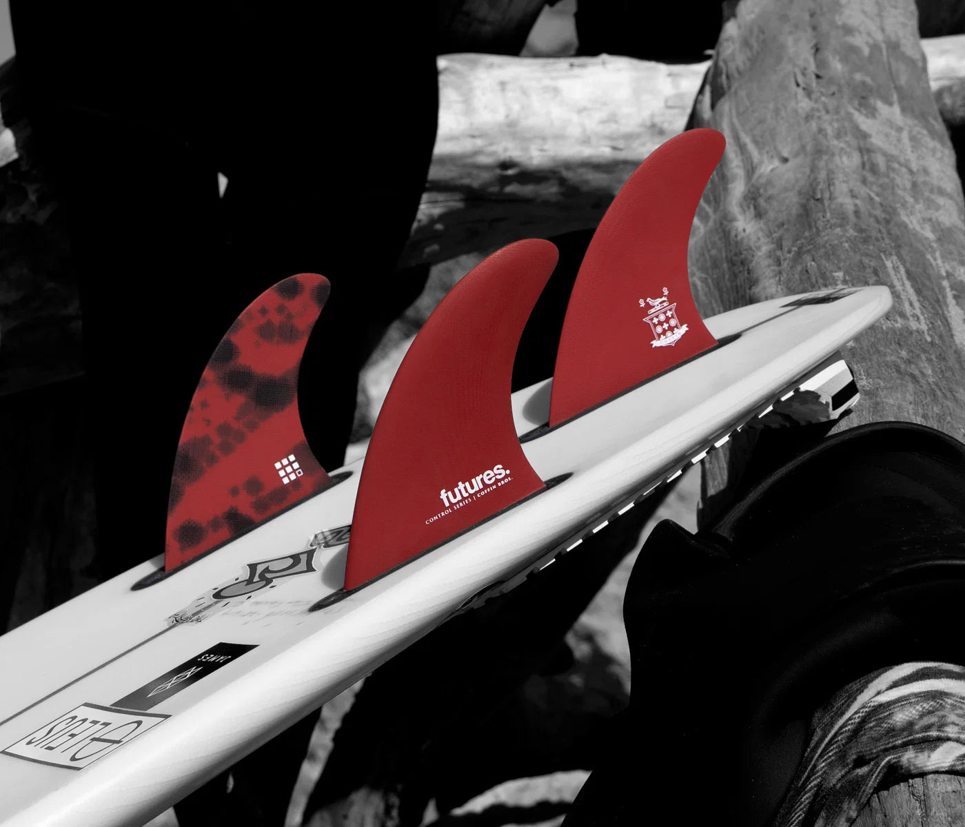 Close-up of a surfboard with red Futures Coffin Bros. Control Series Fiberglass Thruster Fin Set (Medium)