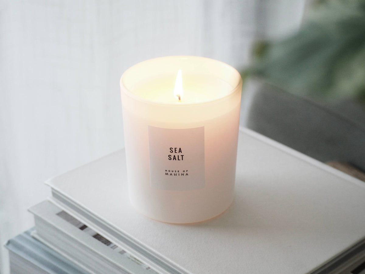 Candle labeled 'Sea Salt' on a surface with a blurred background